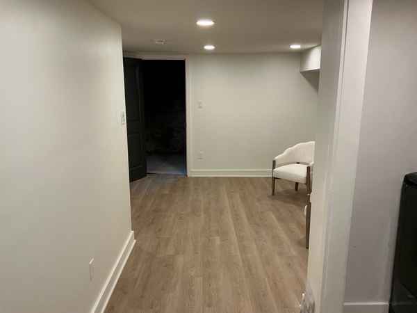 Finished basement with recessed lighting and new vinyl-plank flooring in a flipped rowhouse