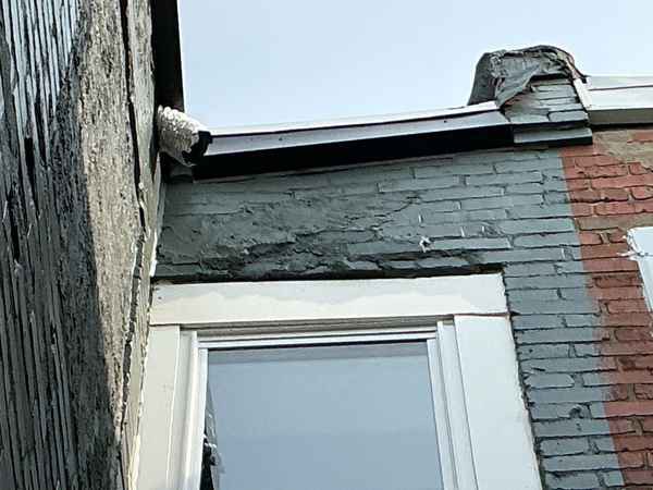 Bowing exterior brick wall with an absent window lintel, flagged for immediate action