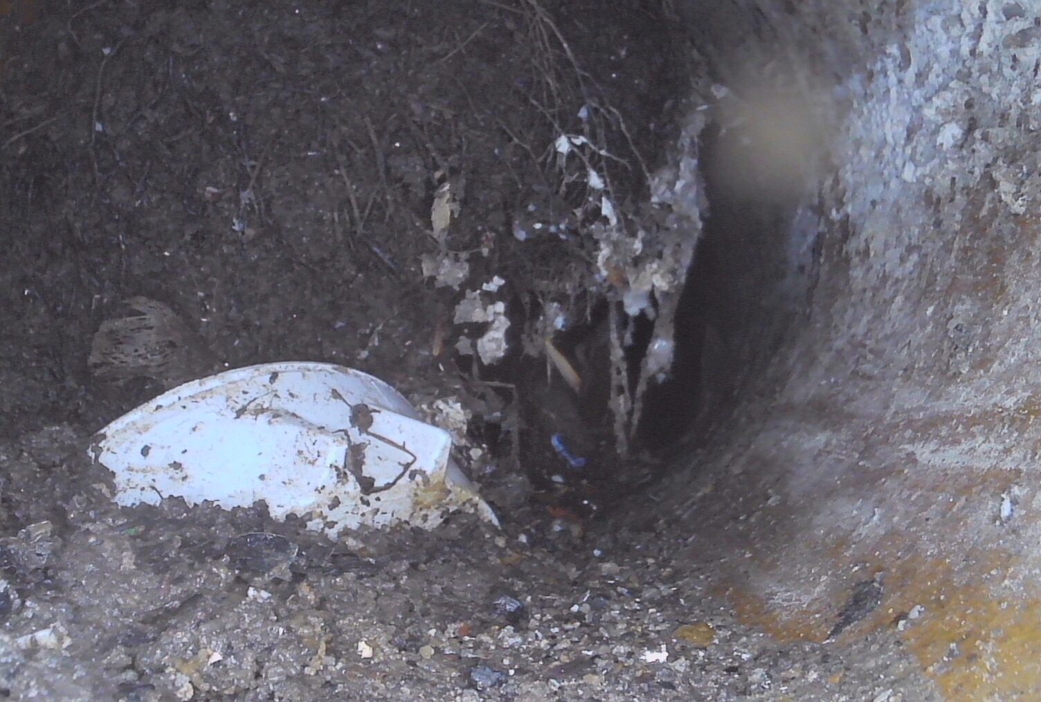 Interior view of a sewer pipe during a sewer scope inspection showing a significant clog of dirt, roots and debris at 46.9 feet along the garage cleanout line