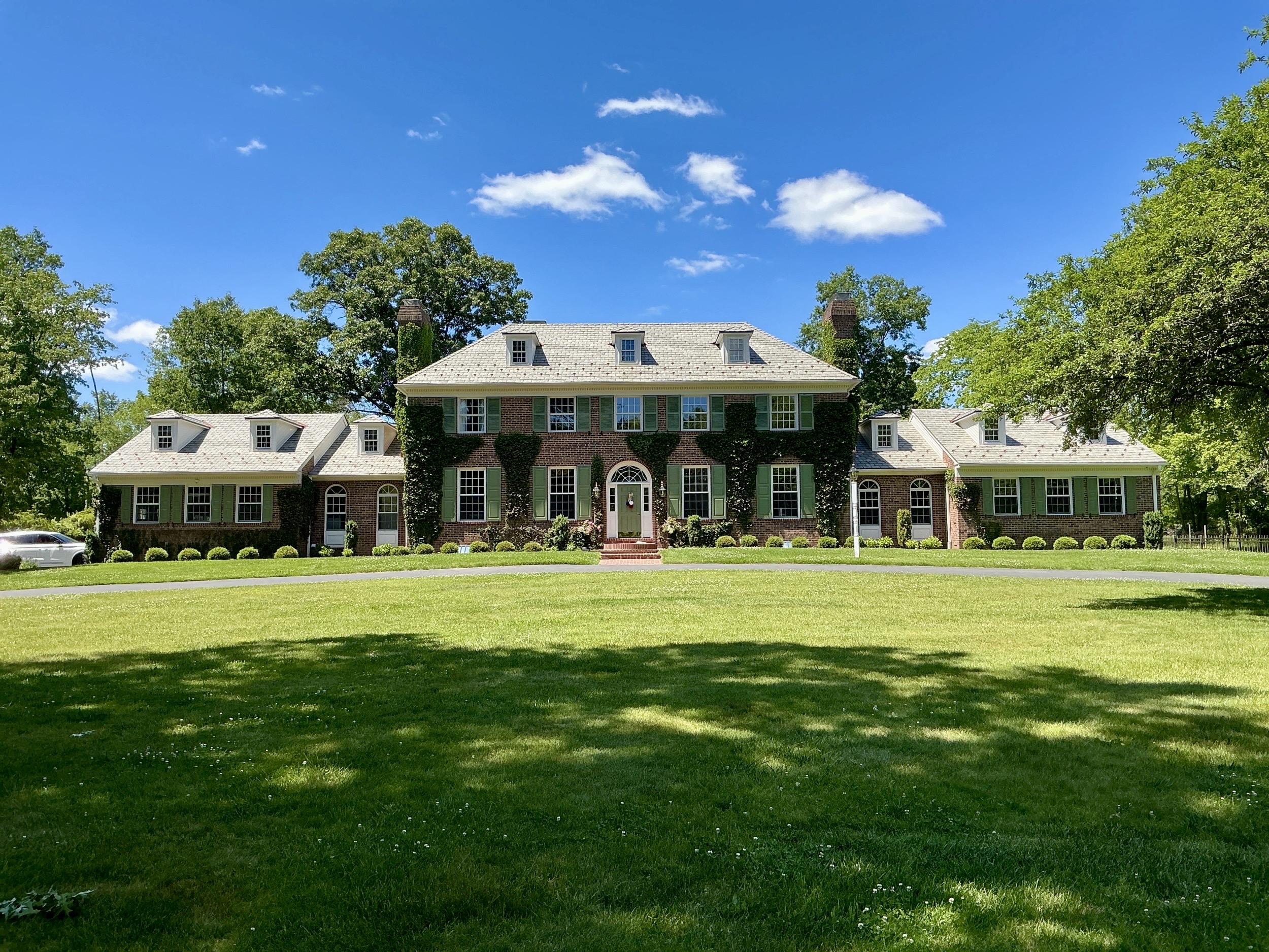 Home inspection by Steven Haslam — large ivy-clad brick colonial estate with green shutters and circular drive in Newtown, Pennsylvania