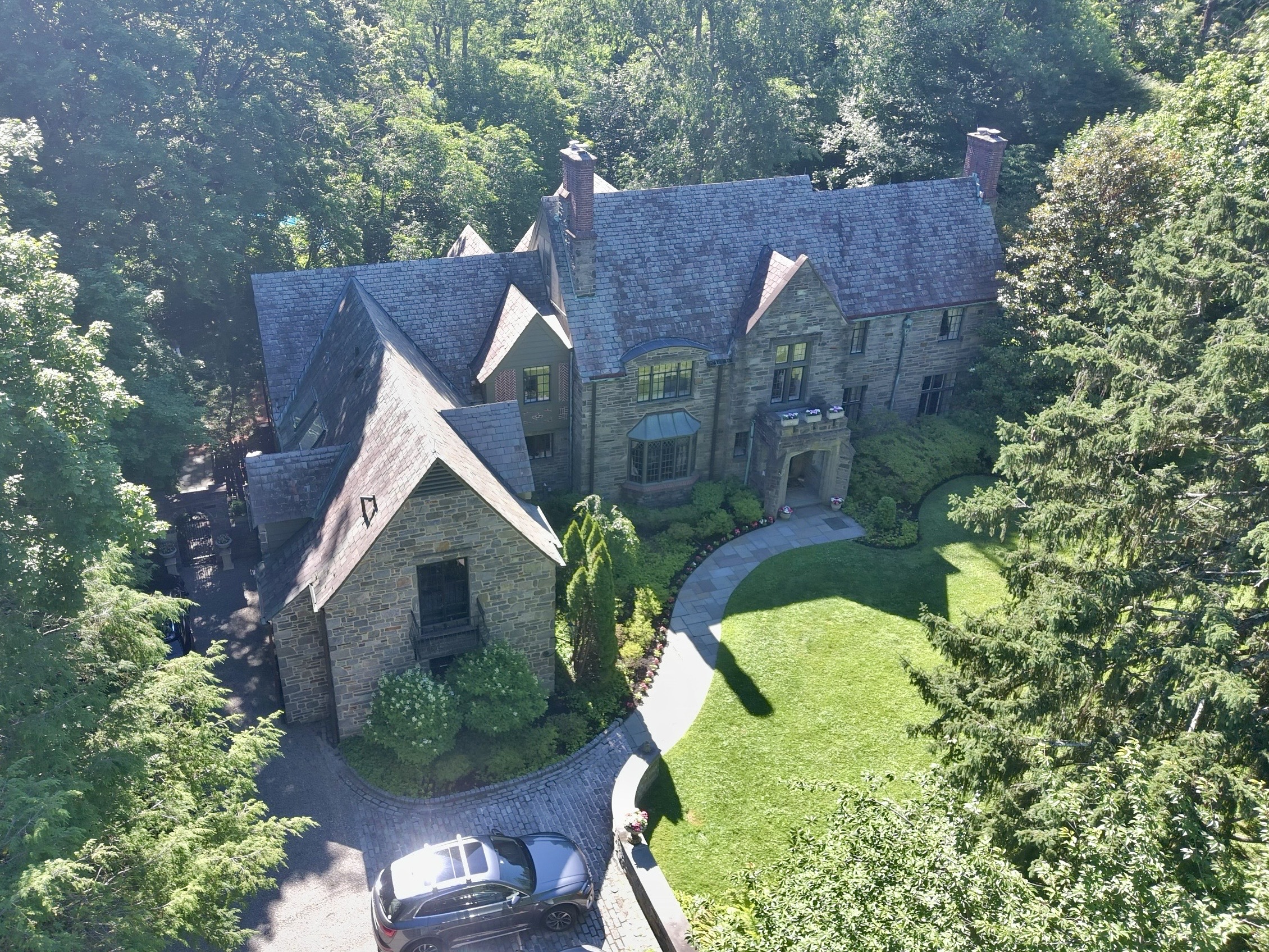 Aerial home inspection by Cory Shalaway — grand stone Tudor with slate roof and multiple gables in Bryn Mawr, Pennsylvania