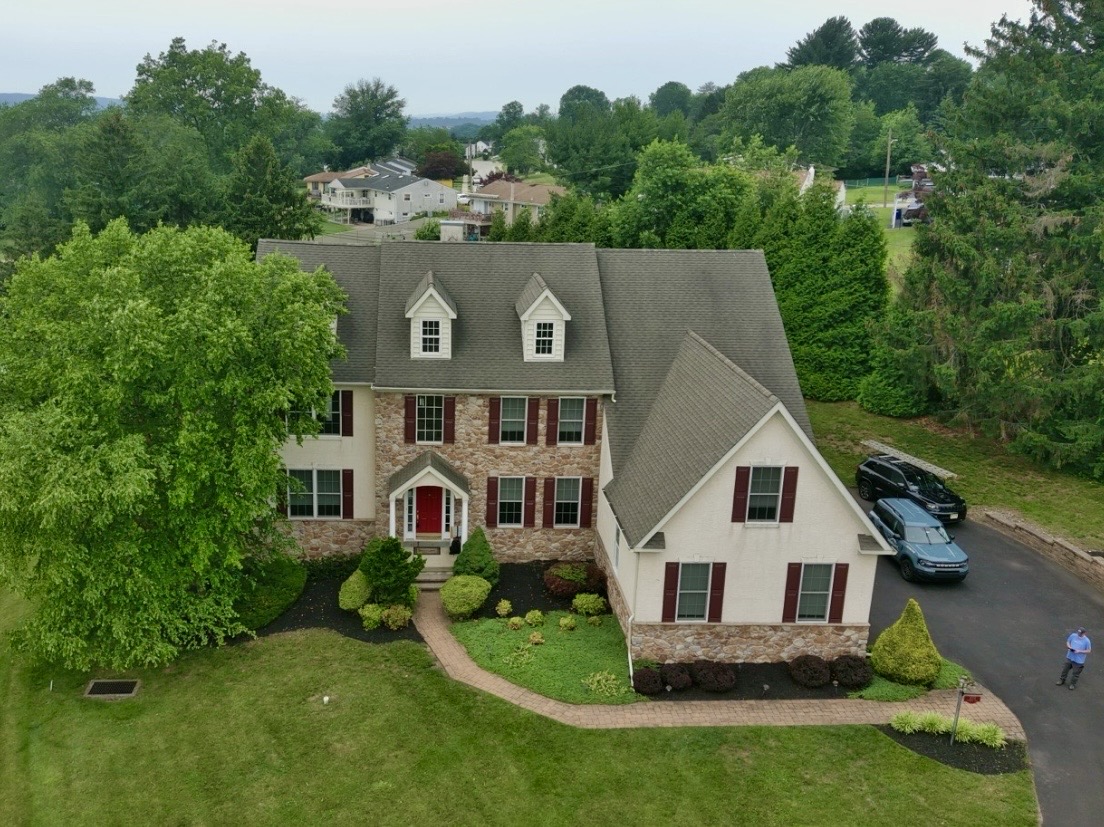 Home inspection by Nick Ostrowski — stone-front colonial with red front door on a wooded suburban lot in Southeastern Pennsylvania