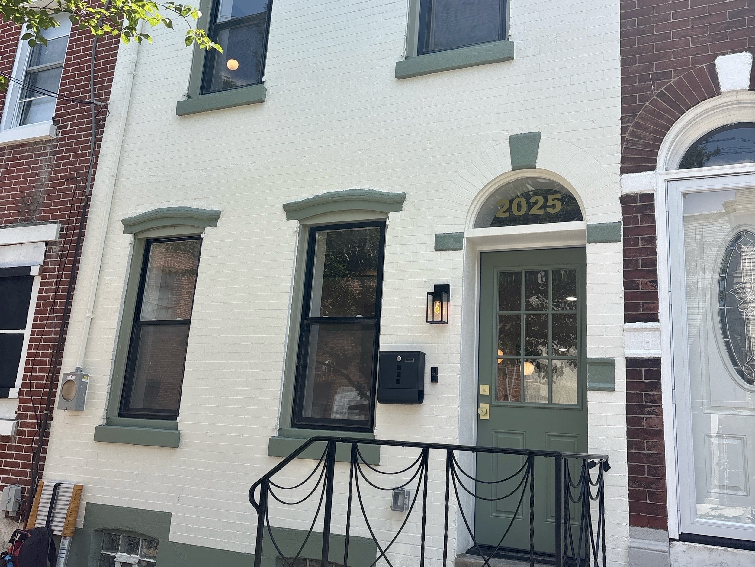 Home inspection by Nick Ostrowski — renovated painted-brick rowhome with green trim and arched transom in Philadelphia