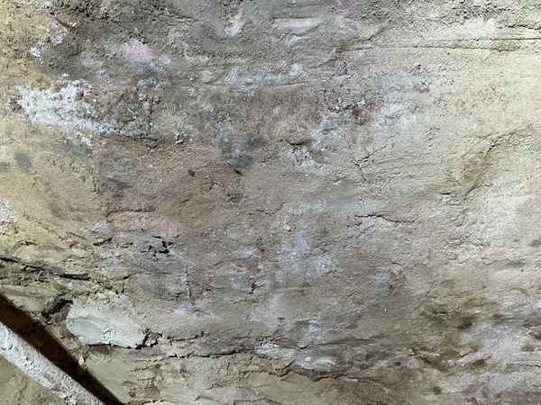 White efflorescence and moisture staining on a stone foundation wall