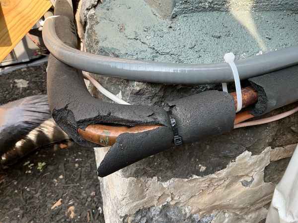Damaged insulation on a new AC refrigerant line set at a heat pump