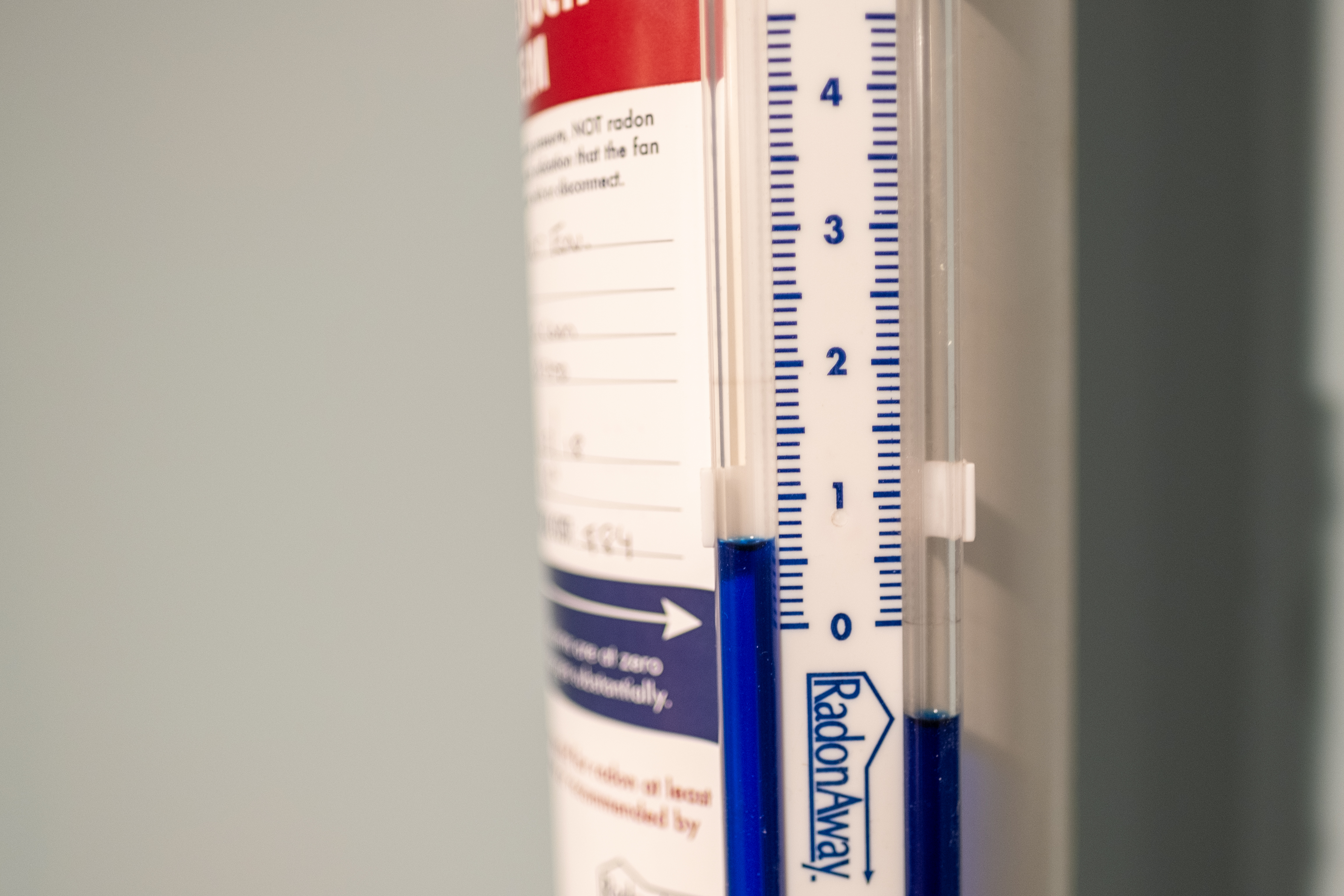 Close-up of a RadonAway radon test kit showing blue liquid level on a measurement scale, used for detecting radon gas levels in homes.