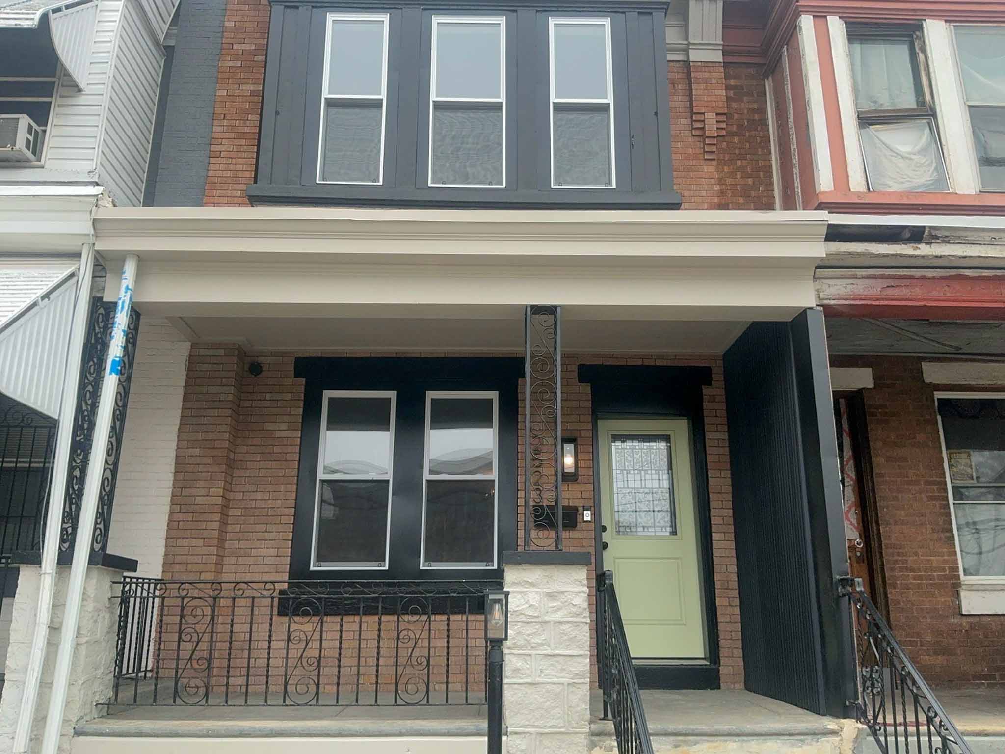 ValueGuard home inspection — recently flipped Brewerytown rowhome with sage green door, ornate scrollwork ironwork, and dark-clad upper level in Philadelphia