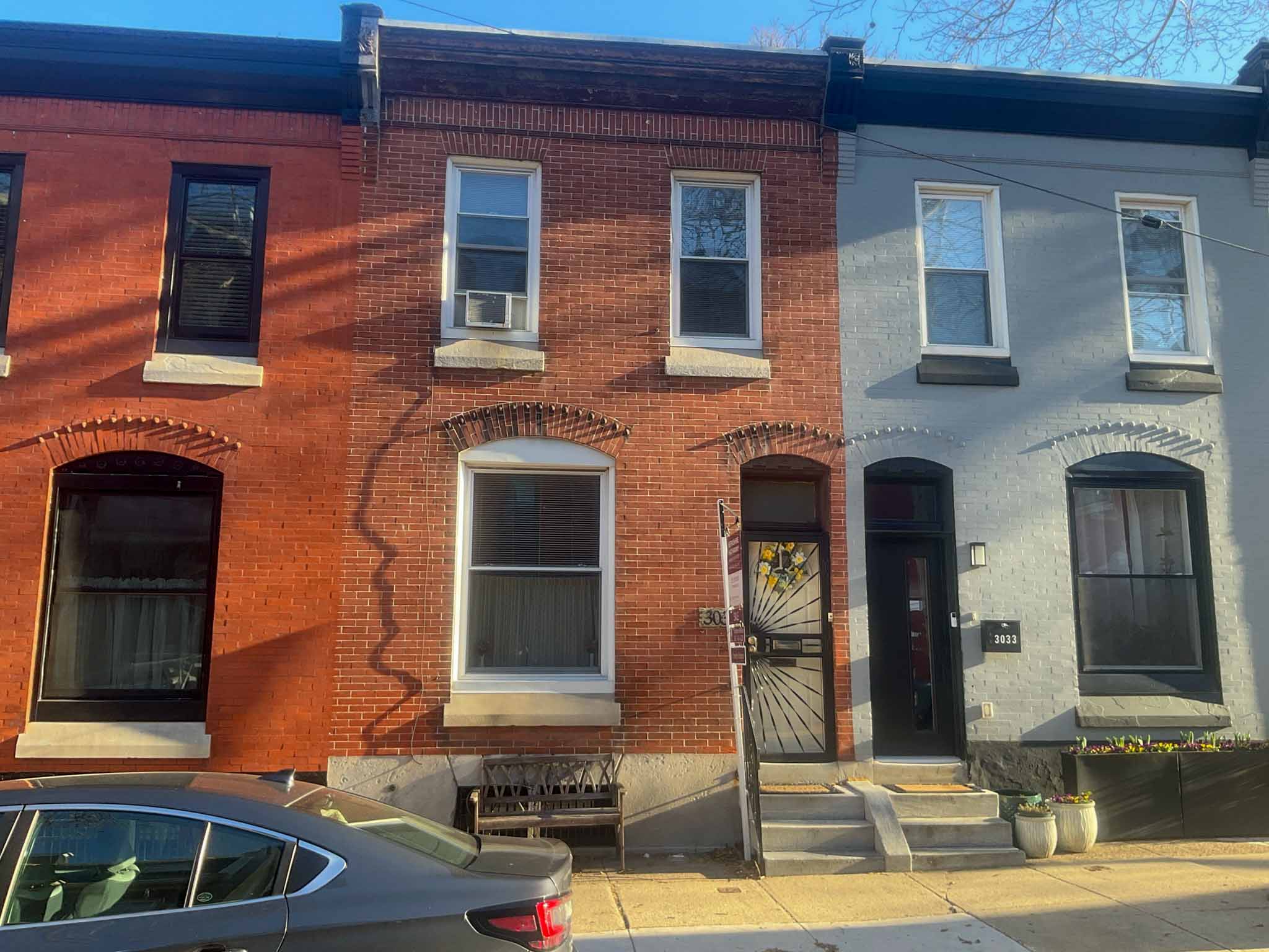 ValueGuard home inspection — three-story painted-red brick Italianate rowhome at 1729 with arched entry, white window hoods, and exposed parged side party wall in Brewerytown Philadelphia