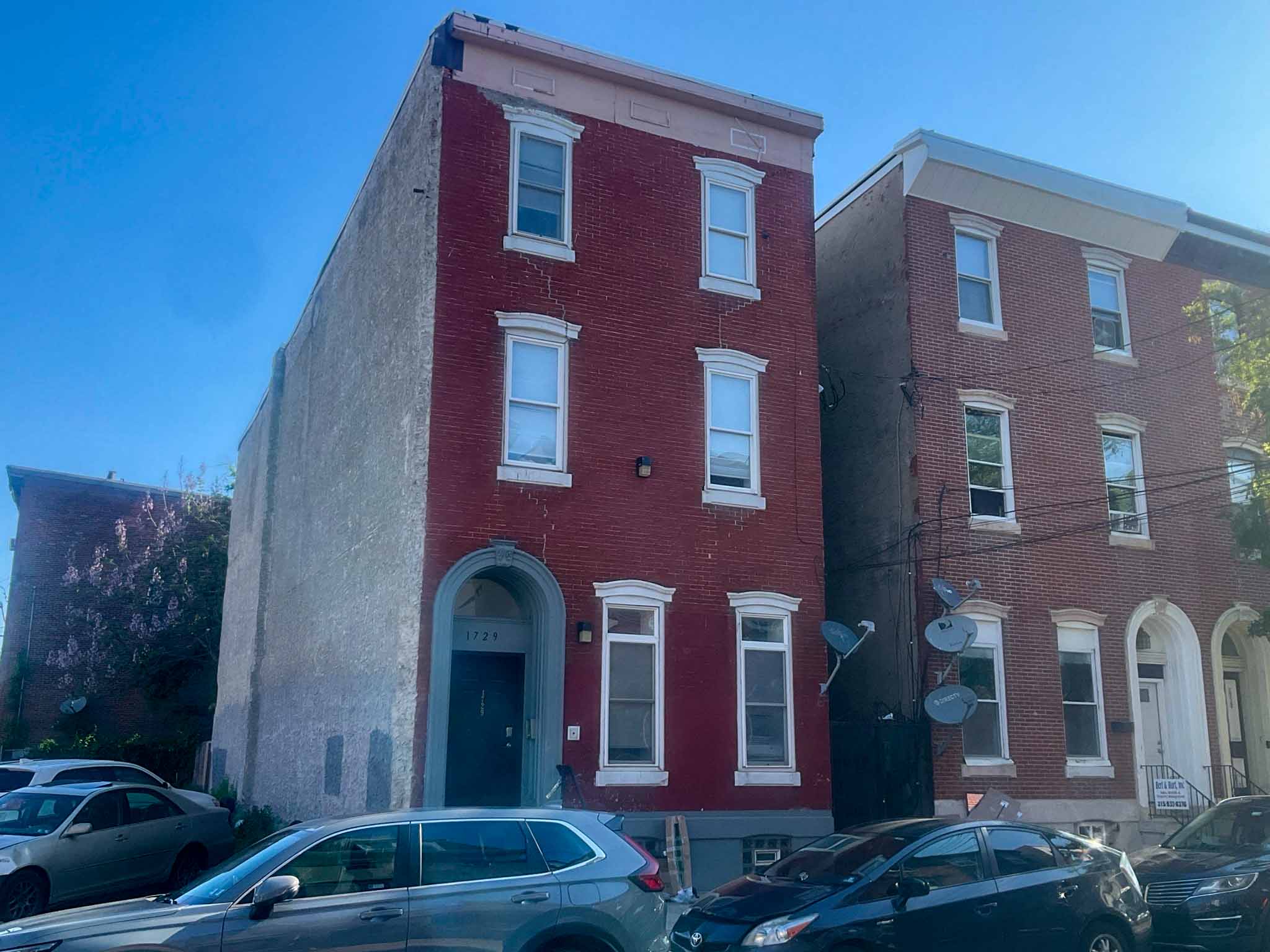 ValueGuard home inspection — two-story brewery-era brick rowhome streetscape with voussoir arches and starburst storm door in Brewerytown Philadelphia