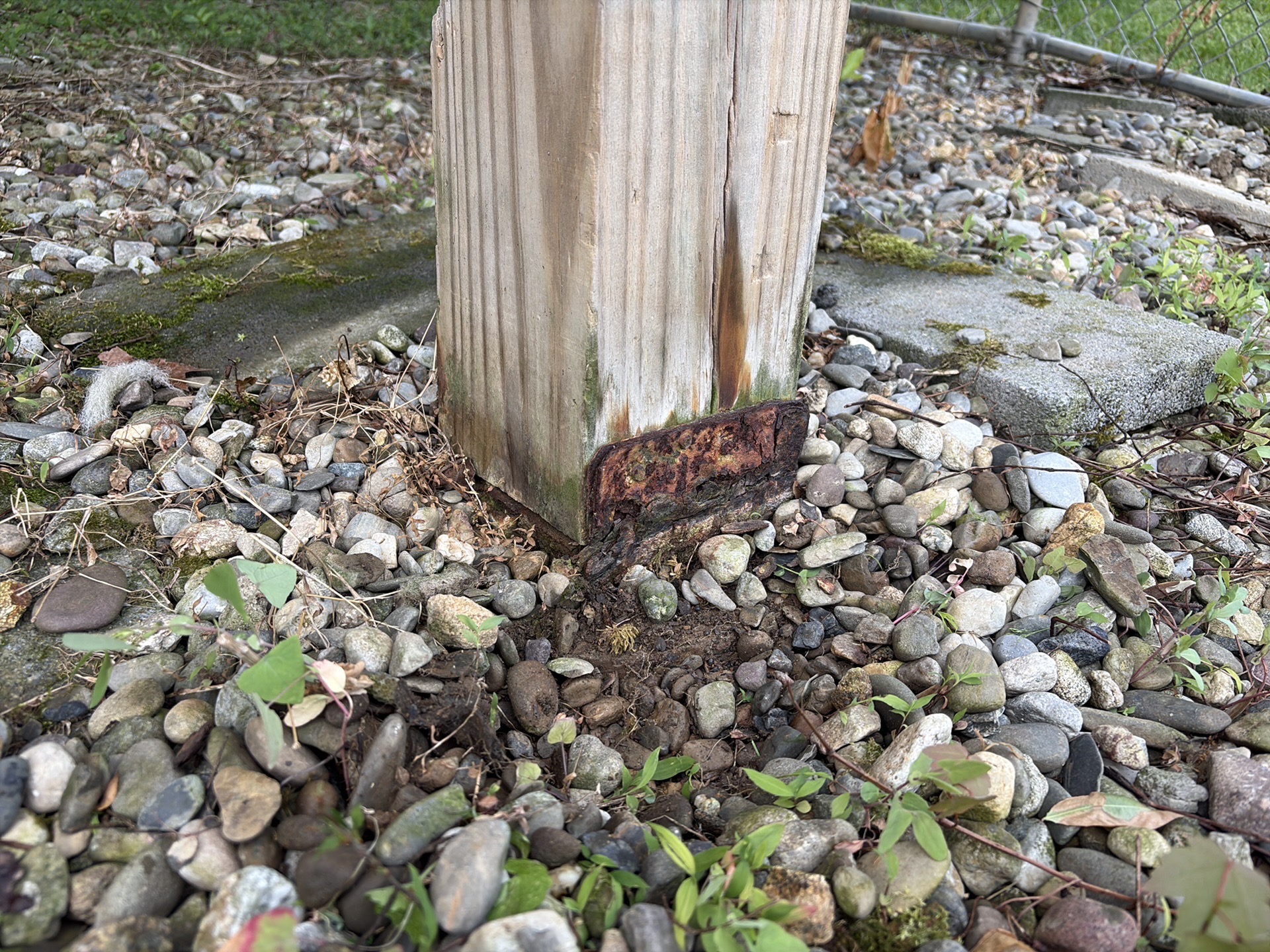 Corroded post bracket and split wood at a deck support post.