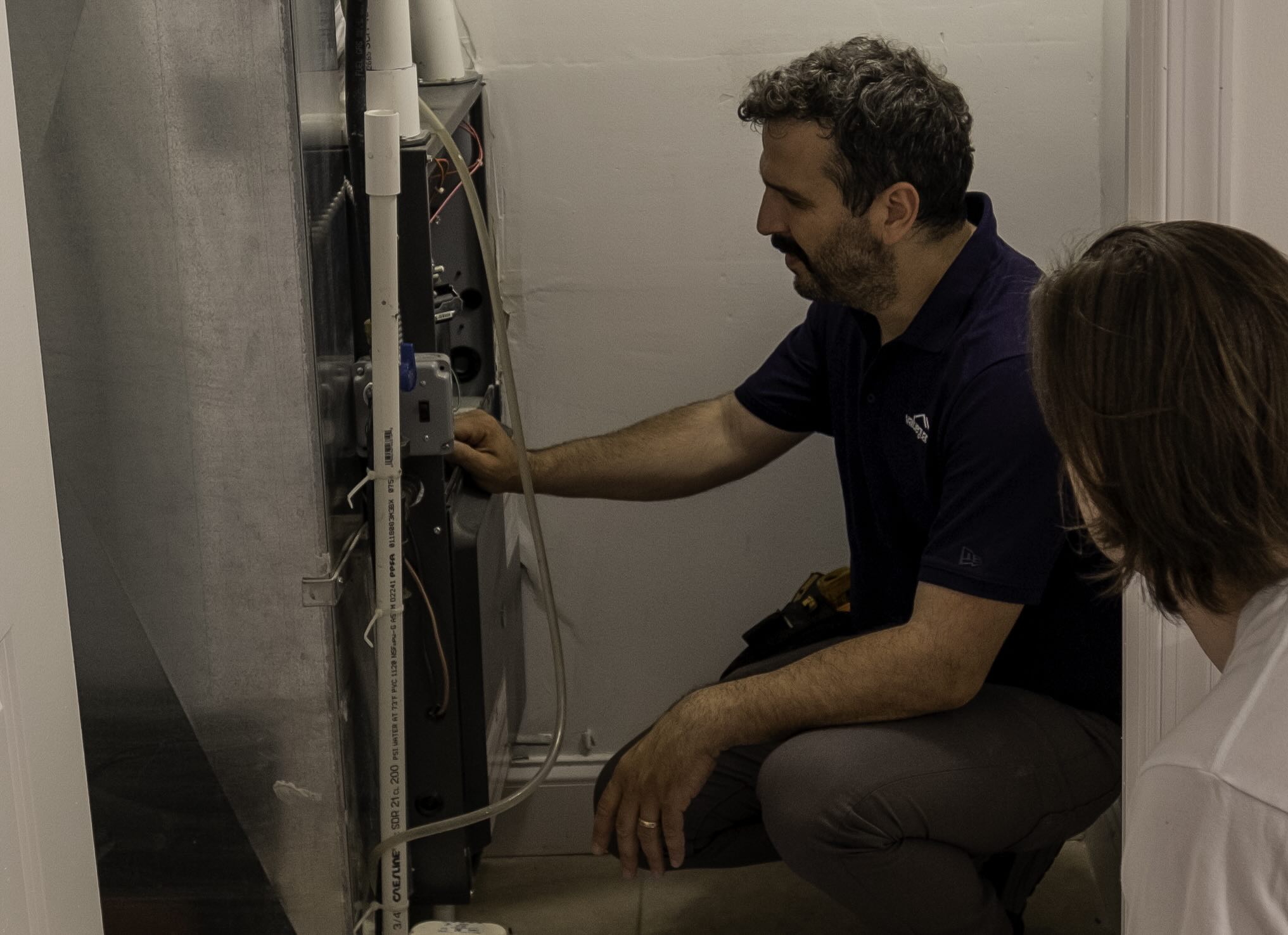 ValueGuard home inspector examining a furnace while explaining his findings to a homebuyer during a pre-offer walk and talk inspection