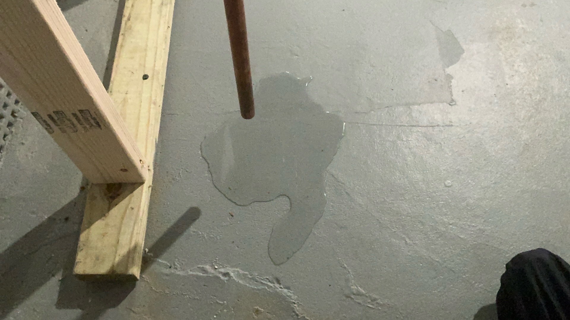 Active water leak from water heater temperature and pressure relief (TPR) valve dripping onto basement concrete floor during DIY home inspection.