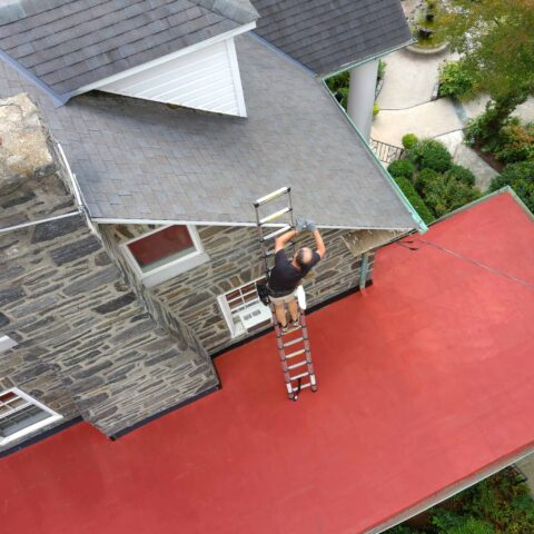 ValueGuard home inspector Michael Kelley inspecting a roof from a ladder during a Philadelphia home inspection