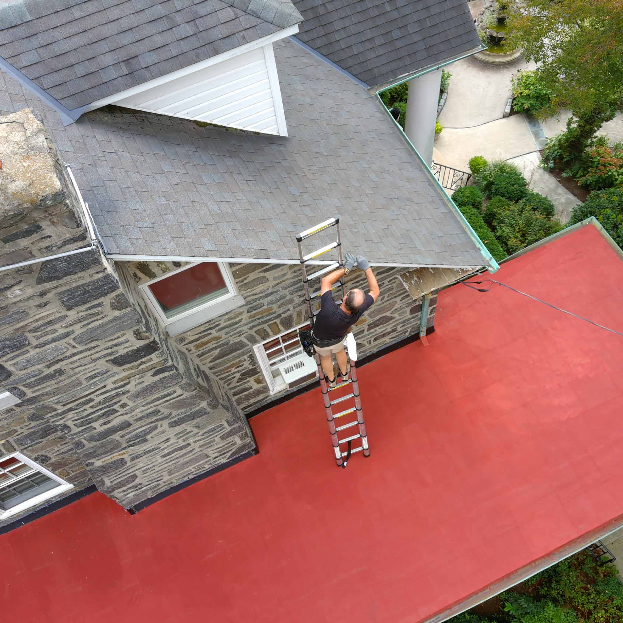 ValueGuard home inspector Michael Kelley inspecting a roof from a ladder during a Philadelphia home inspection