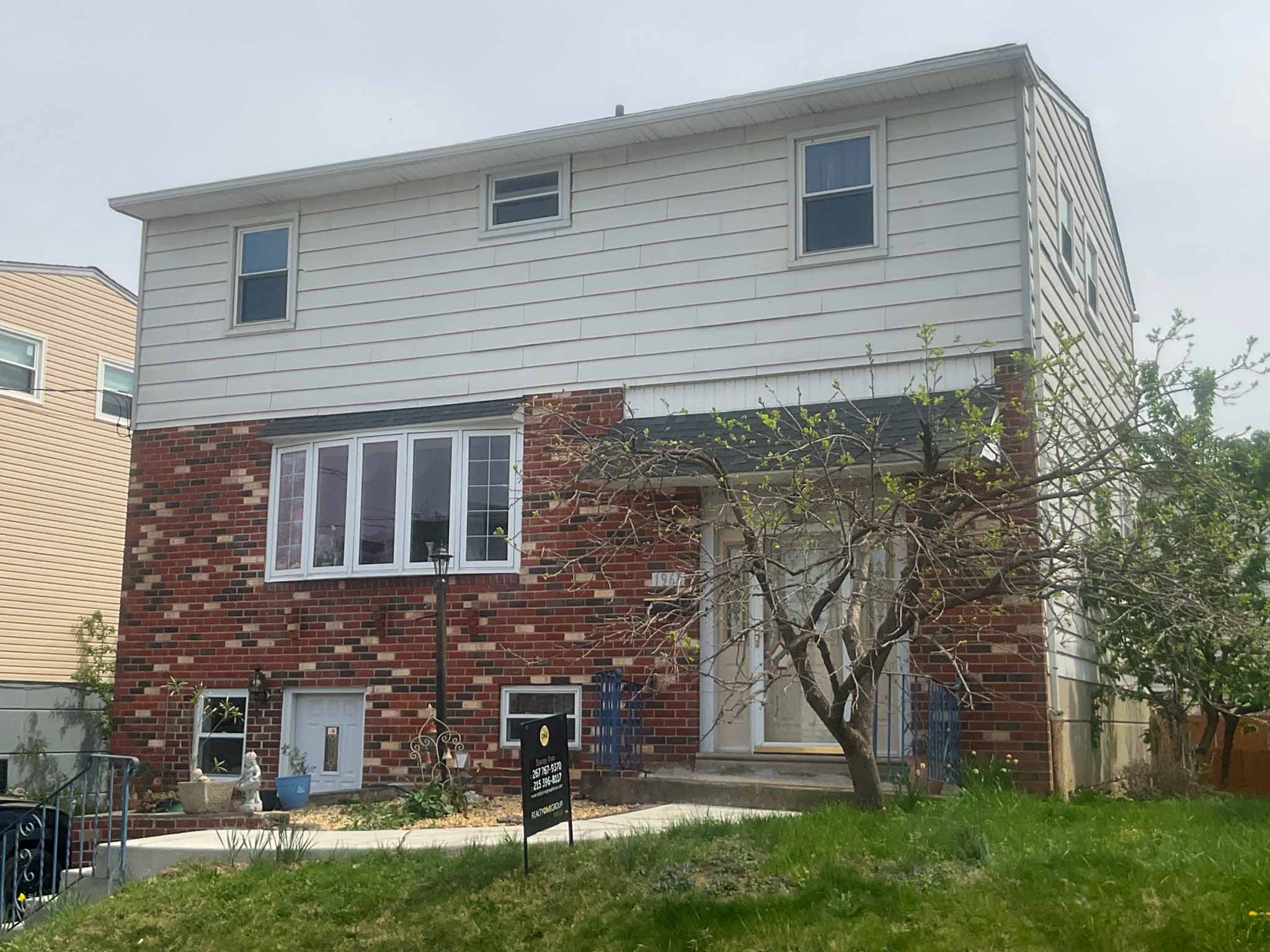 ValueGuard home inspection — 1920s Tudor-trim brick rowhome with elaborate cream limestone arched entry and stone-trimmed window surrounds at 1327 in the Lower Northeast Philadelphia