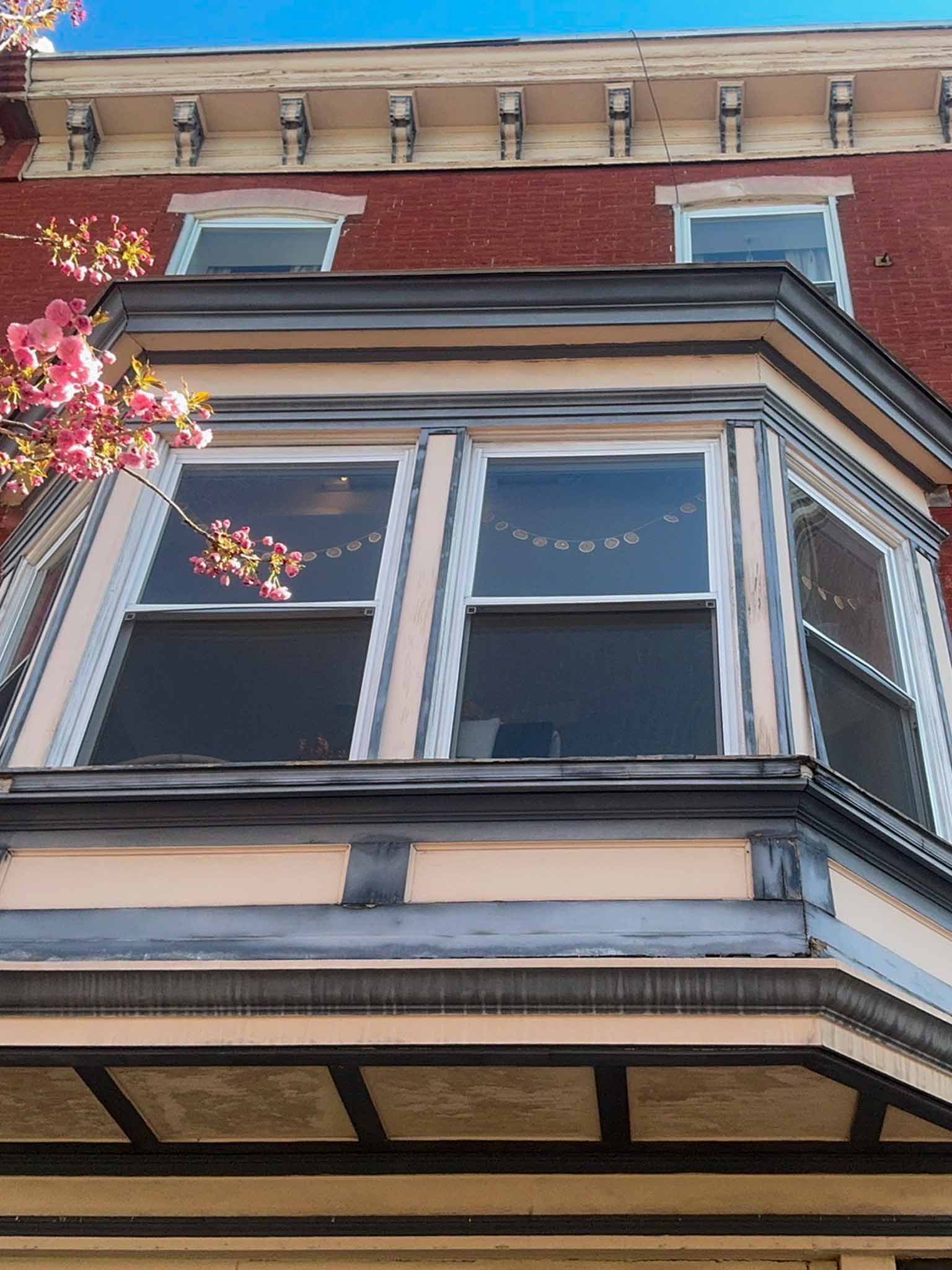 ValueGuard home inspection — peach-painted brick Victorian twin with original enclosed wraparound front porch, dark-red beveled wood door, and bracketed cornice in University City Philadelphia