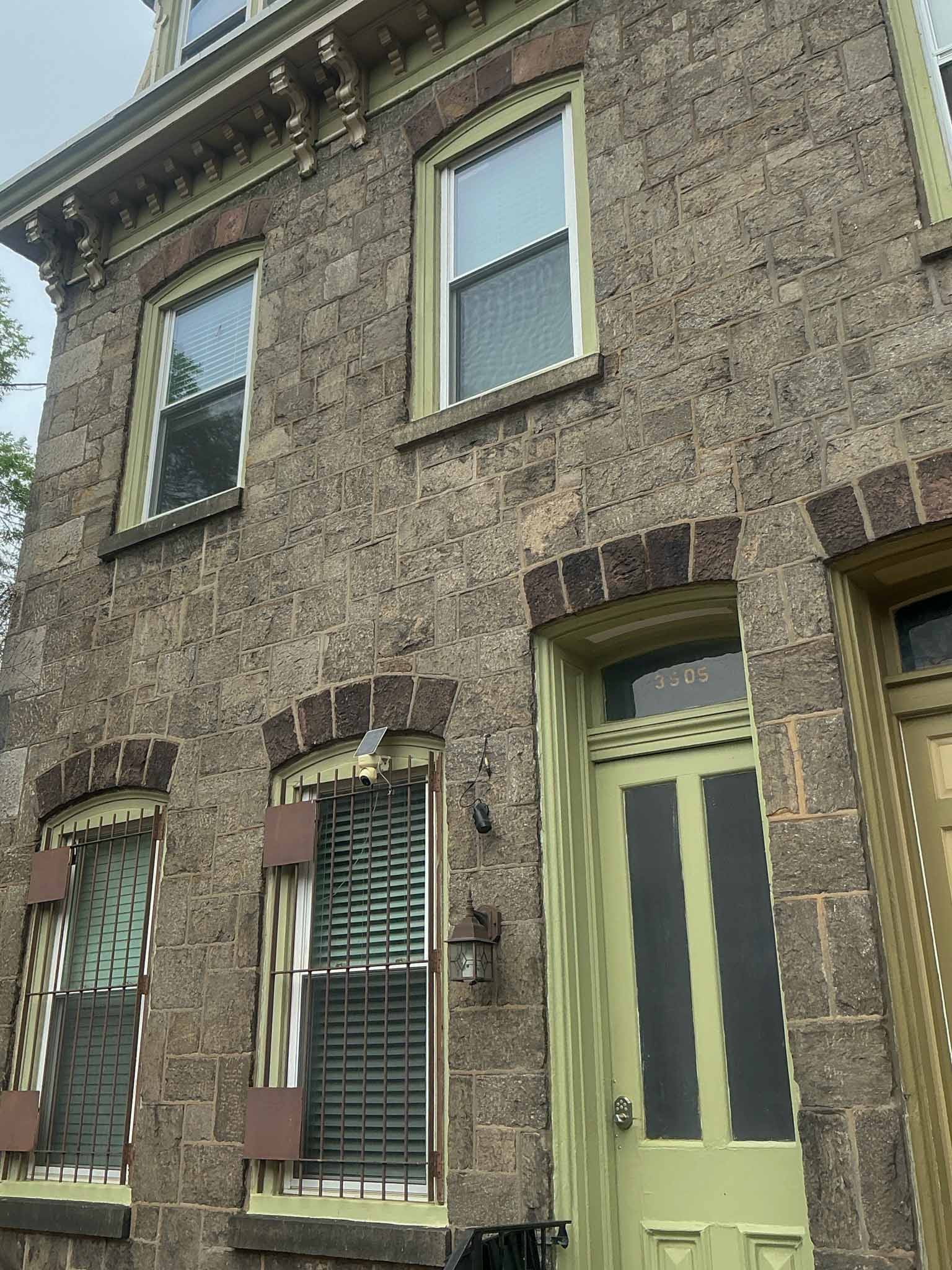 ValueGuard home inspection — 1880s Wissahickon schist Victorian twin at 3505 with brownstone voussoirs, ornate carved wood brackets at cornice, and green-painted trim in University City Philadelphia