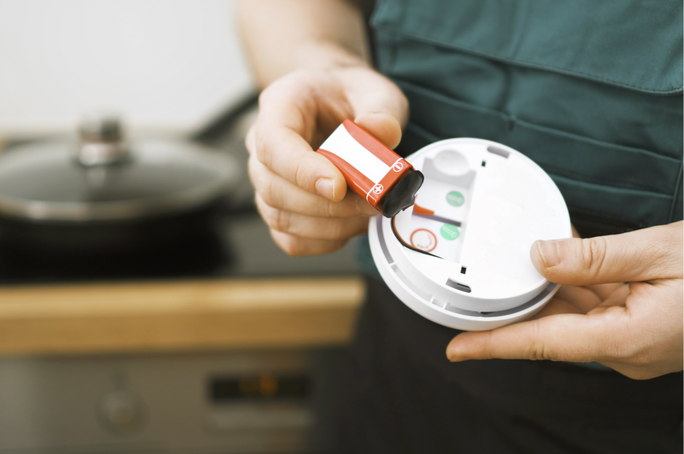 Homeowner replacing the battery in a ceiling-mounted smoke detector