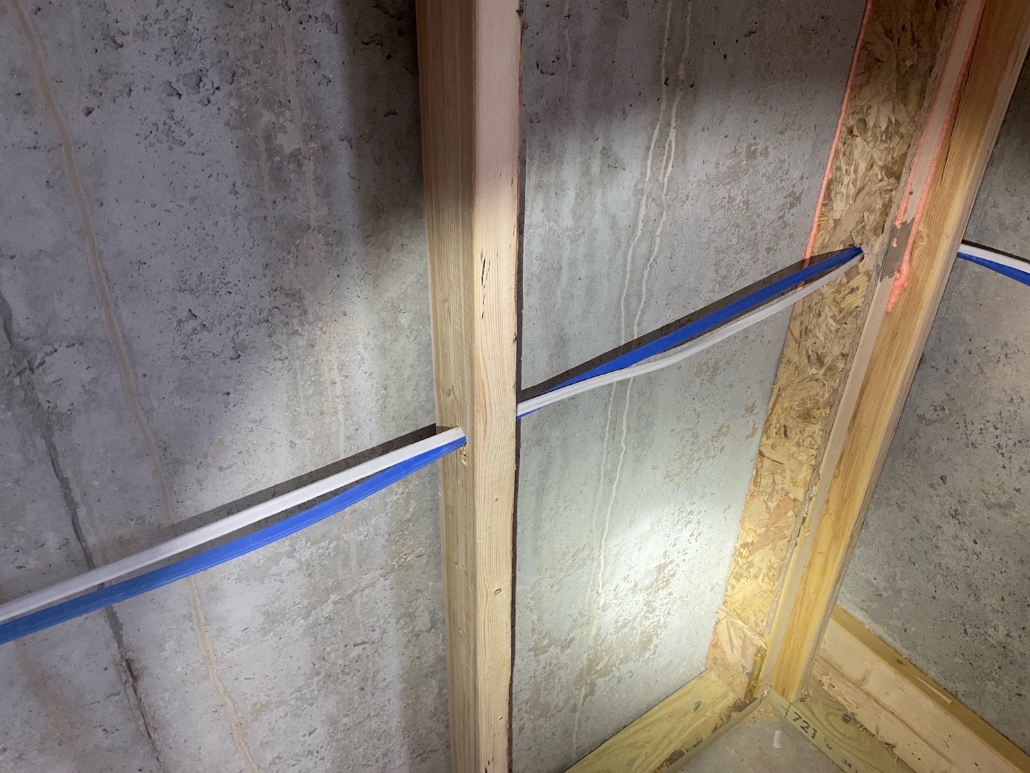 Wiring and PEX lines crossing a wood stud with no nail-protection plates installed, noted during a pre-drywall inspection