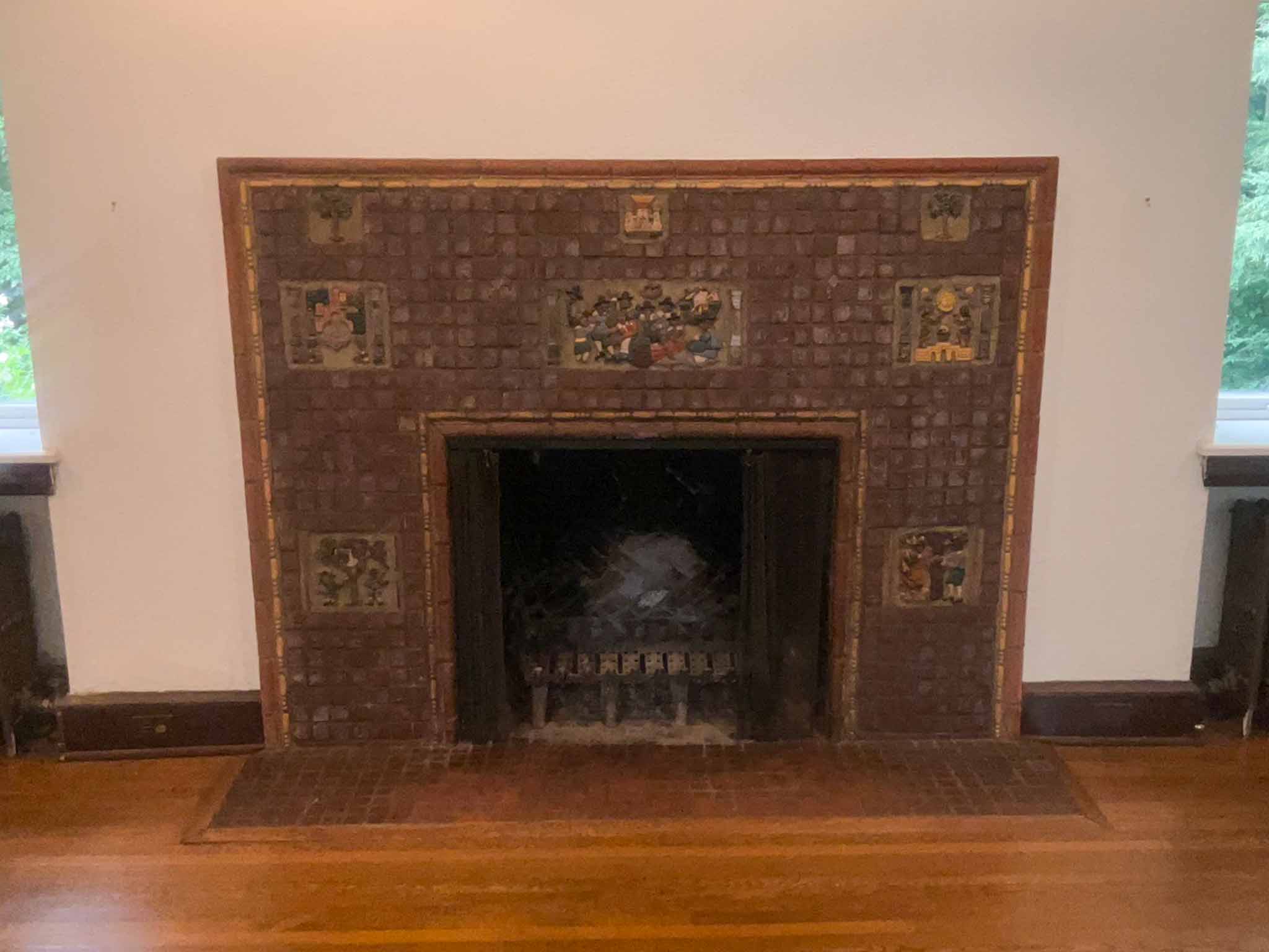 Handmade decorative tile fireplace surround with figural relief panels in a 1927 Tudor Revival home flanked by original radiators