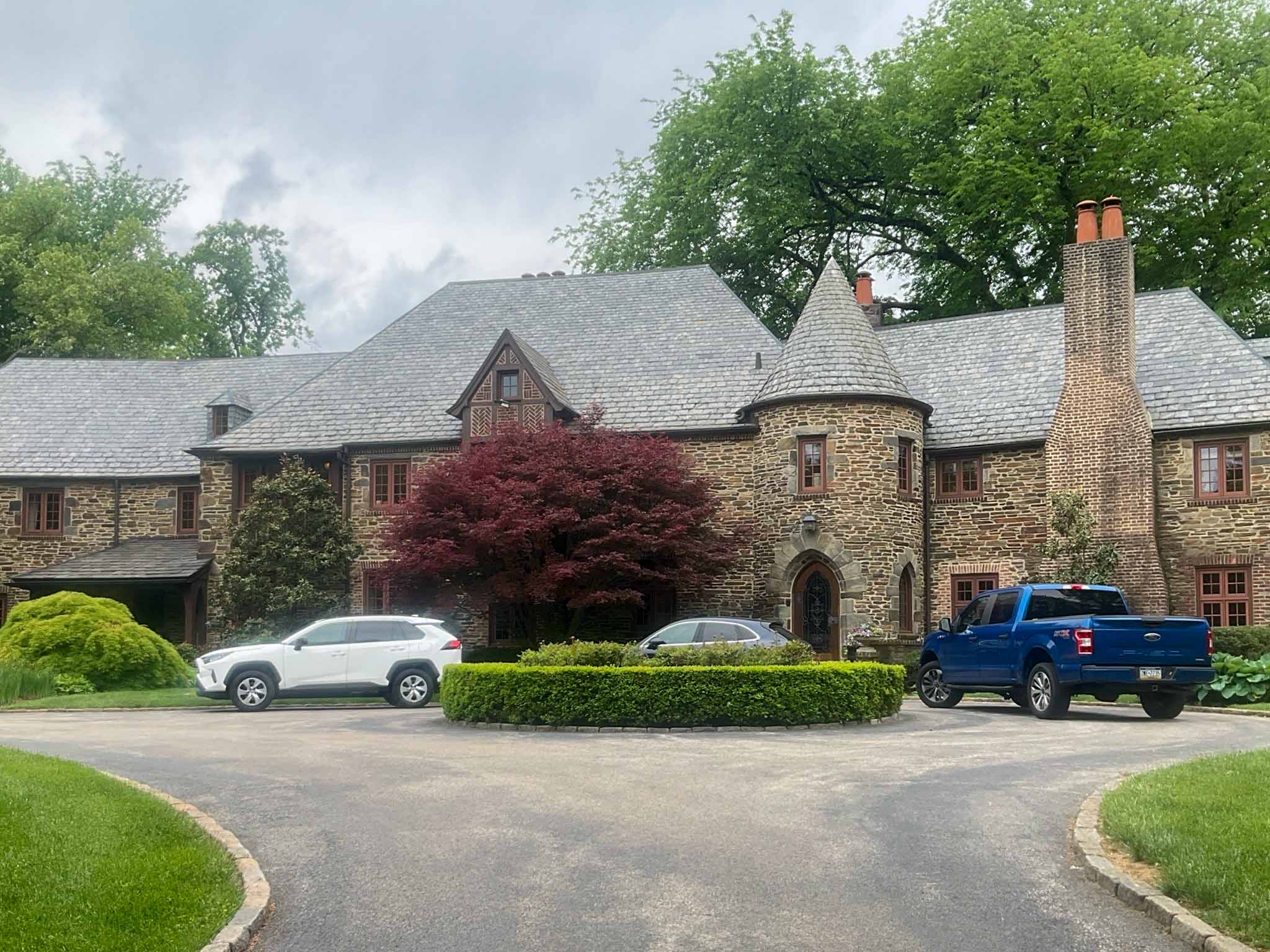 Landmark stone Tudor manor with a slate roof, conical turret and clay-pot chimneys in Bryn Mawr inspected by ValueGuard
