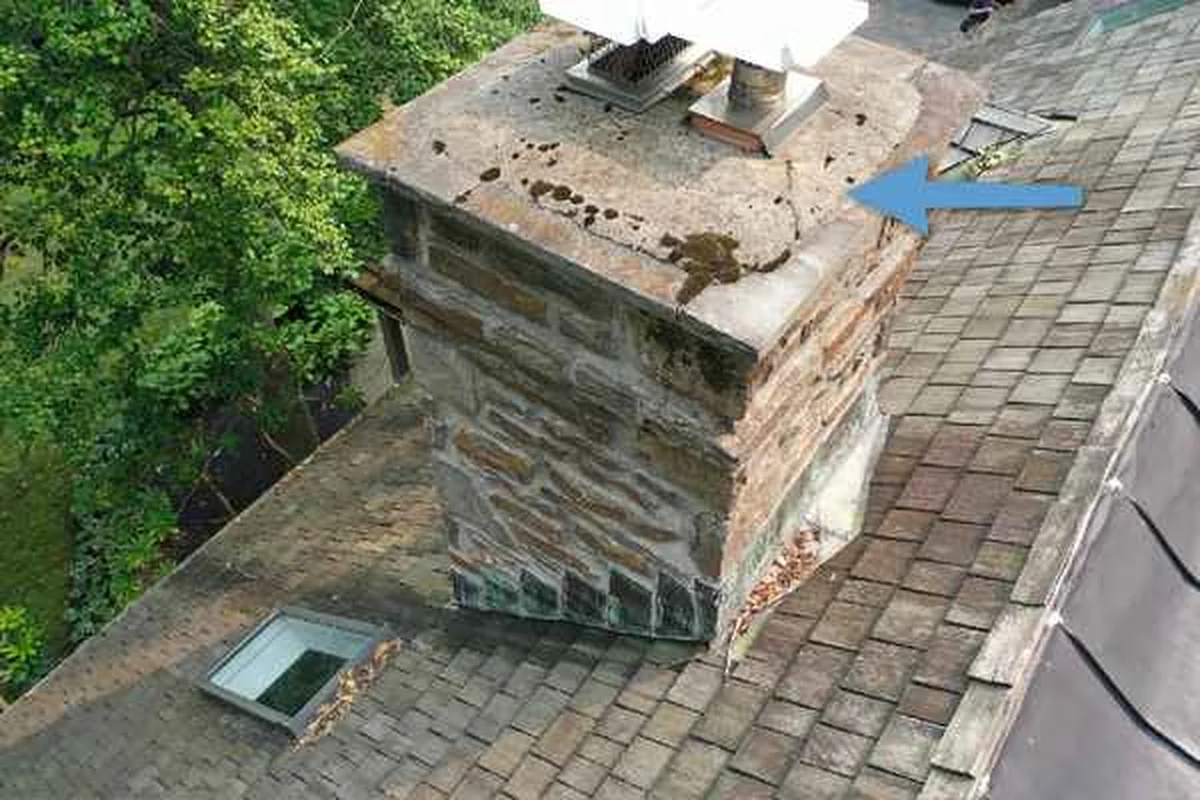 Damaged masonry chimney crown photographed by drone during a home inspection