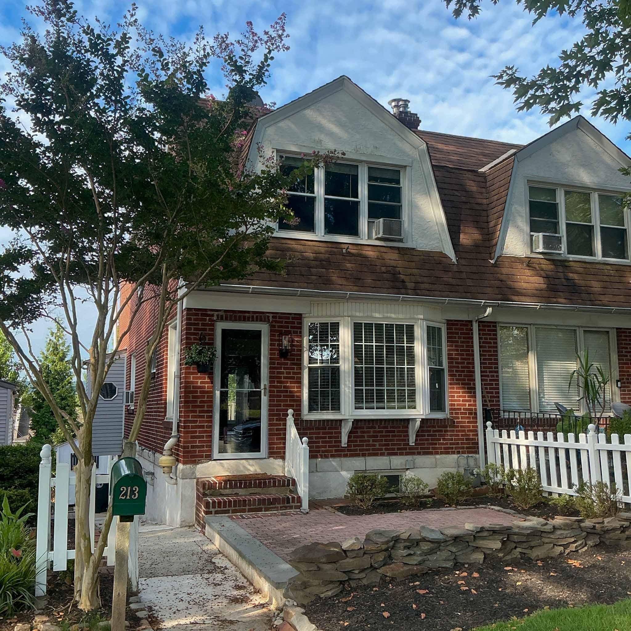 Historic red brick row home with a gambrel roof and bay window in Conshohocken Borough inspected by a ValueGuard home inspector