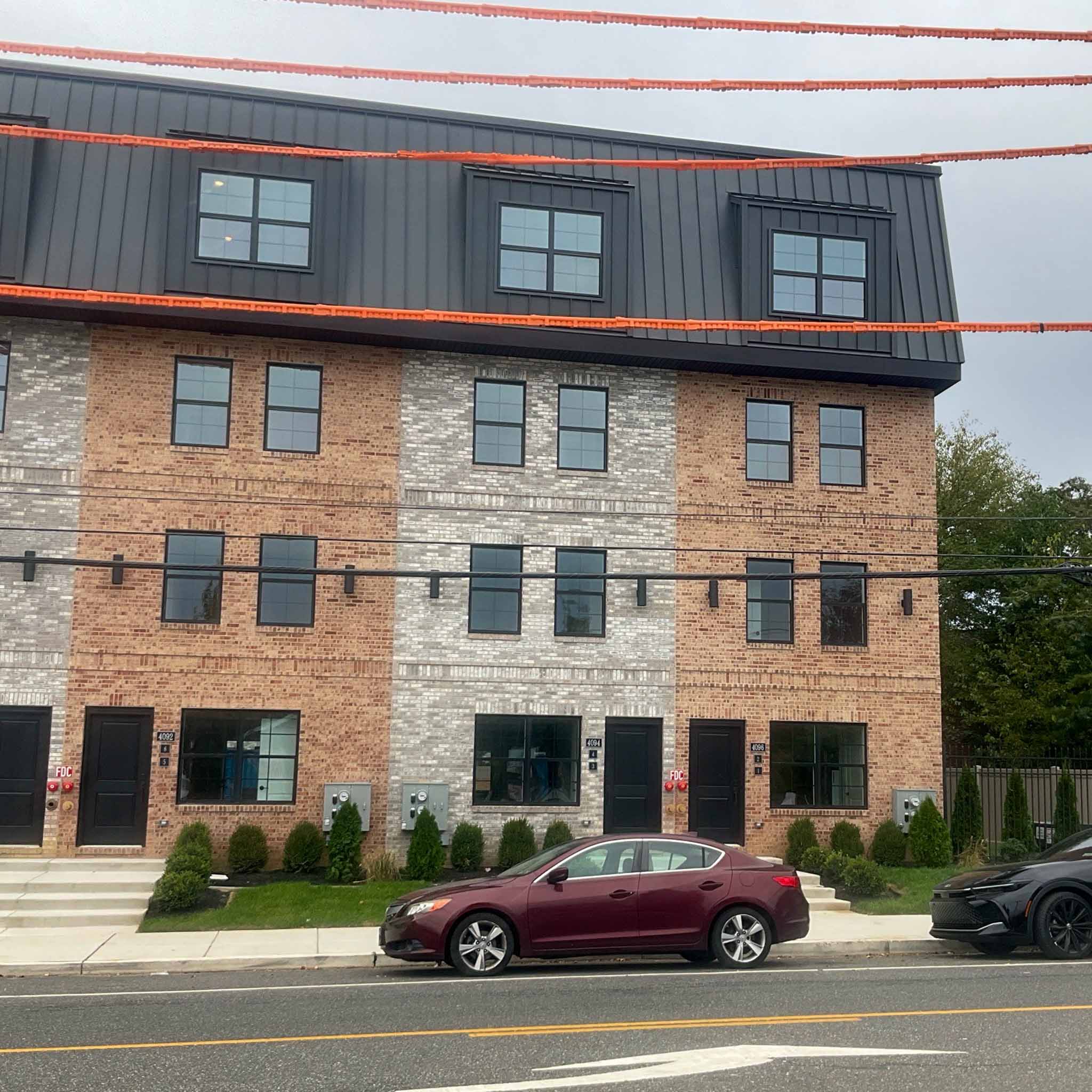 Block of brand-new construction brick rowhomes with a standing-seam mansard in Conshohocken inspected by ValueGuard
