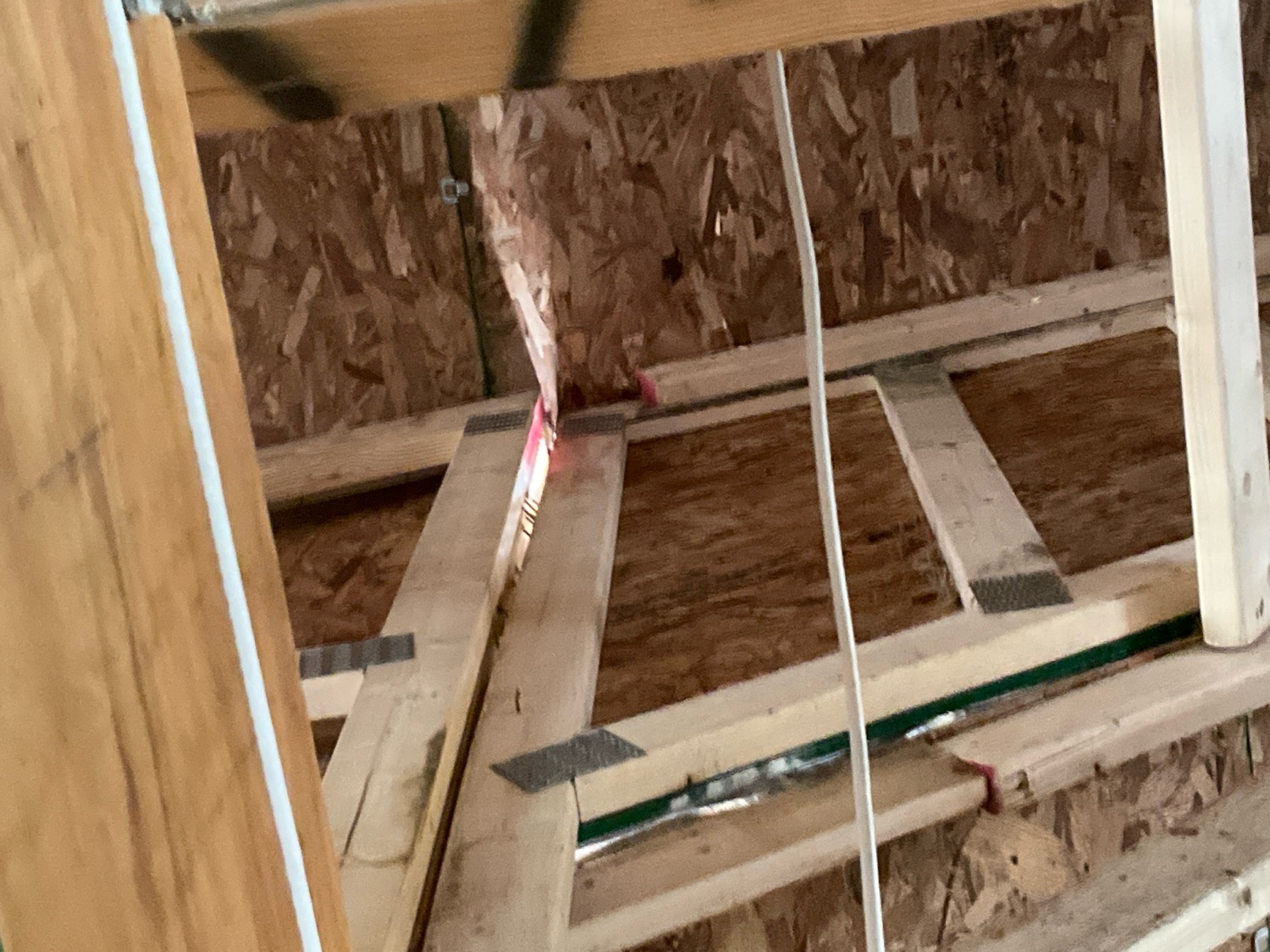 Daylight visible through a gap in the roof sheathing seen from inside the attic during a pre-drywall inspection