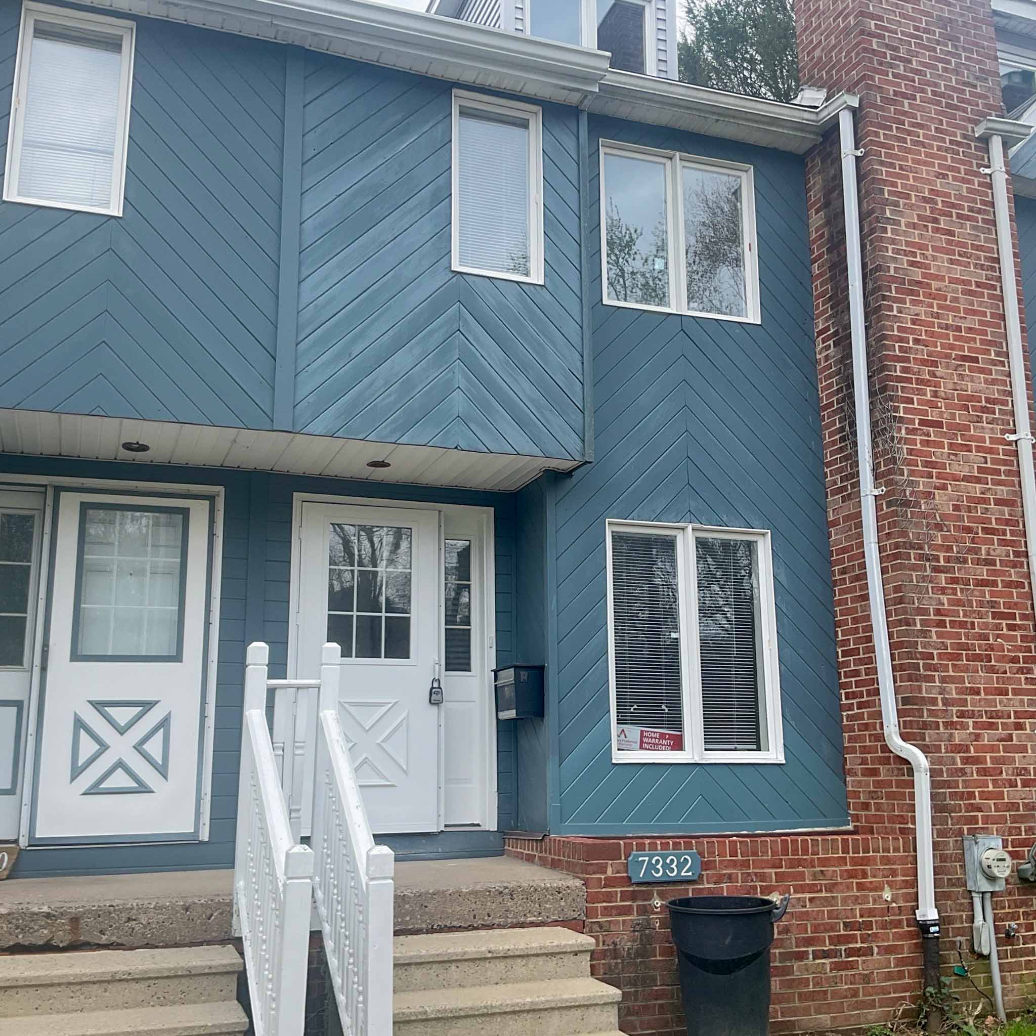 Devon Home Inspection — Older Townhome Older Main Line townhome with blue diagonal wood siding and a brick party-wall chimney in Devon, Chester County PA, inspected by a ValueGuard home inspector