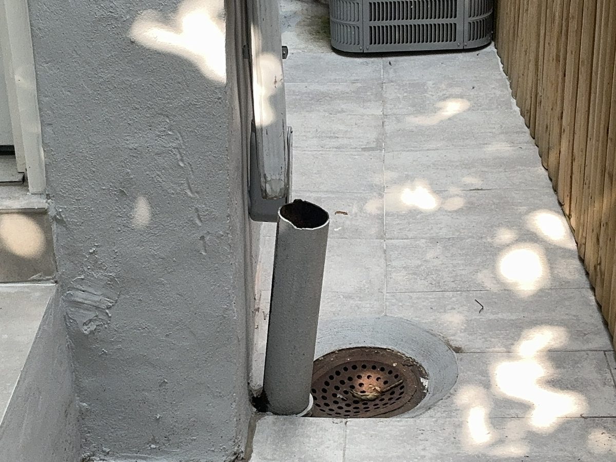 Downspout disconnected and ending short of an exterior drain