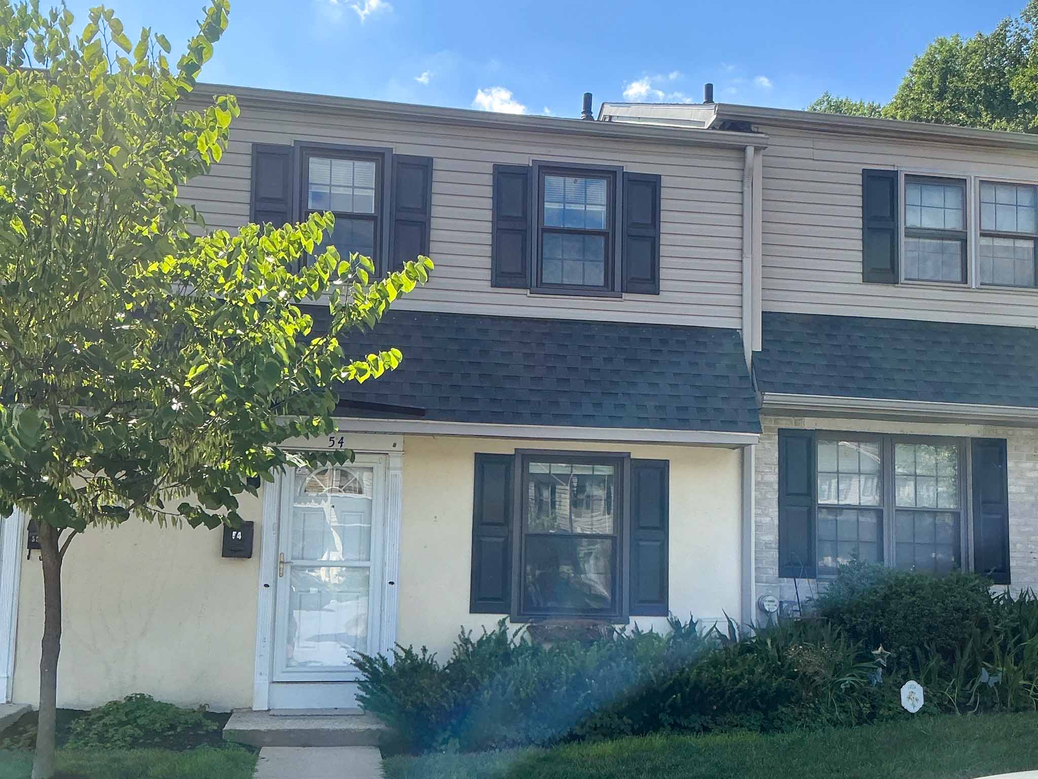 Brown clapboard two-story colonial with dark shutters, front dormer and a new architectural shingle roof on a wooded lot in Downingtown, Chester County PA, inspected by a ValueGuard home inspector
