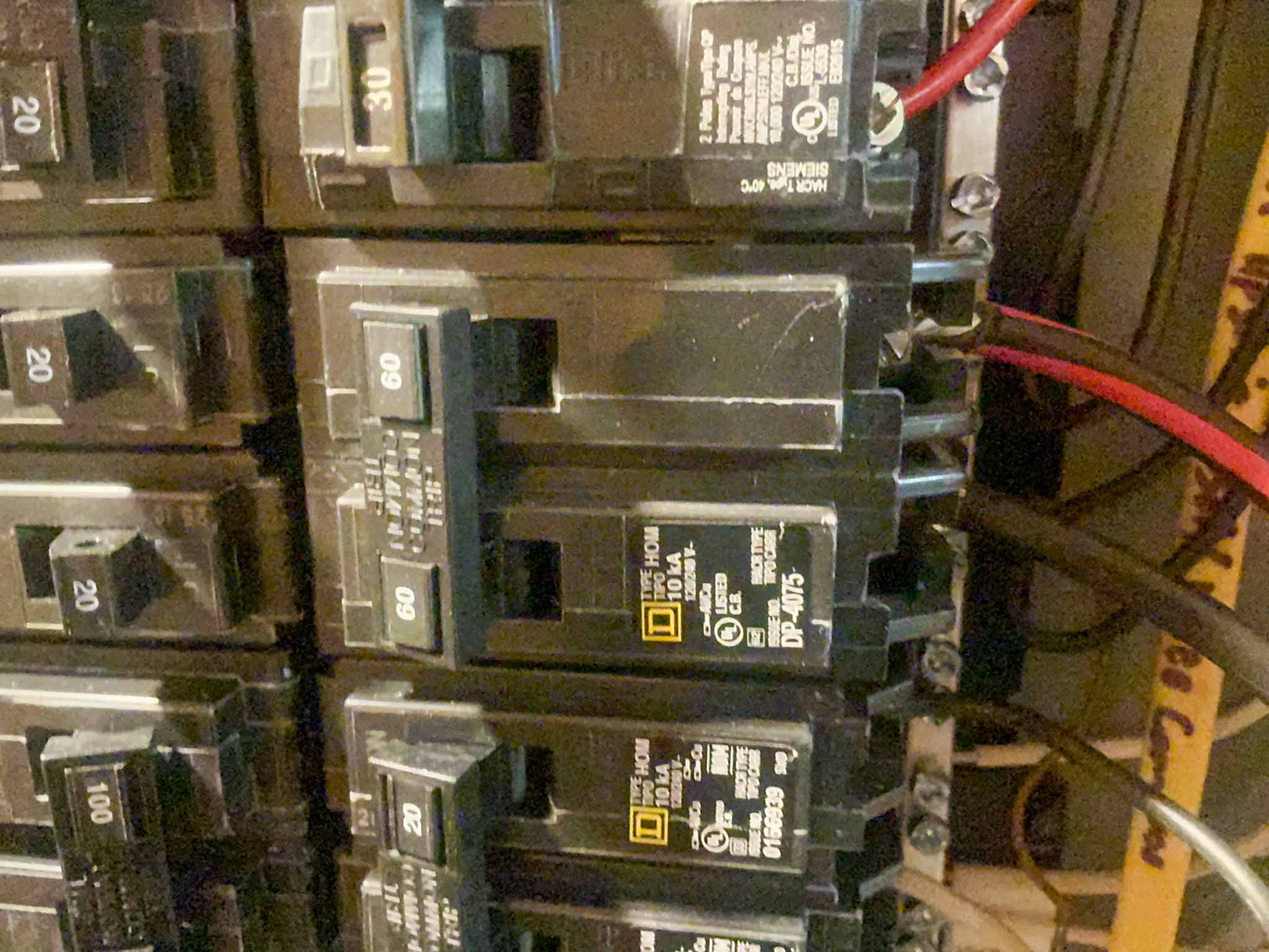 Inside of an electrical panel showing mixed-brand breakers, including double-tapped and non-listed devices, at an Aston PA home inspection