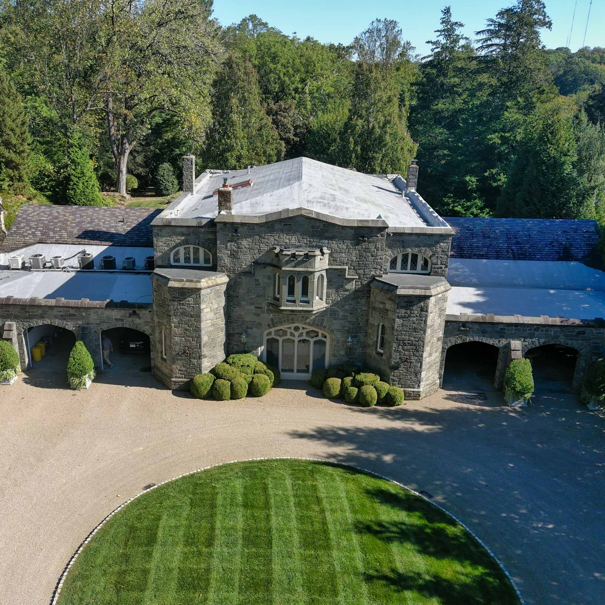 Aerial view of a grand gray stone manor with twin towers and arched carriage bays during a ValueGuard home inspection in Gladwyne on the Main Line