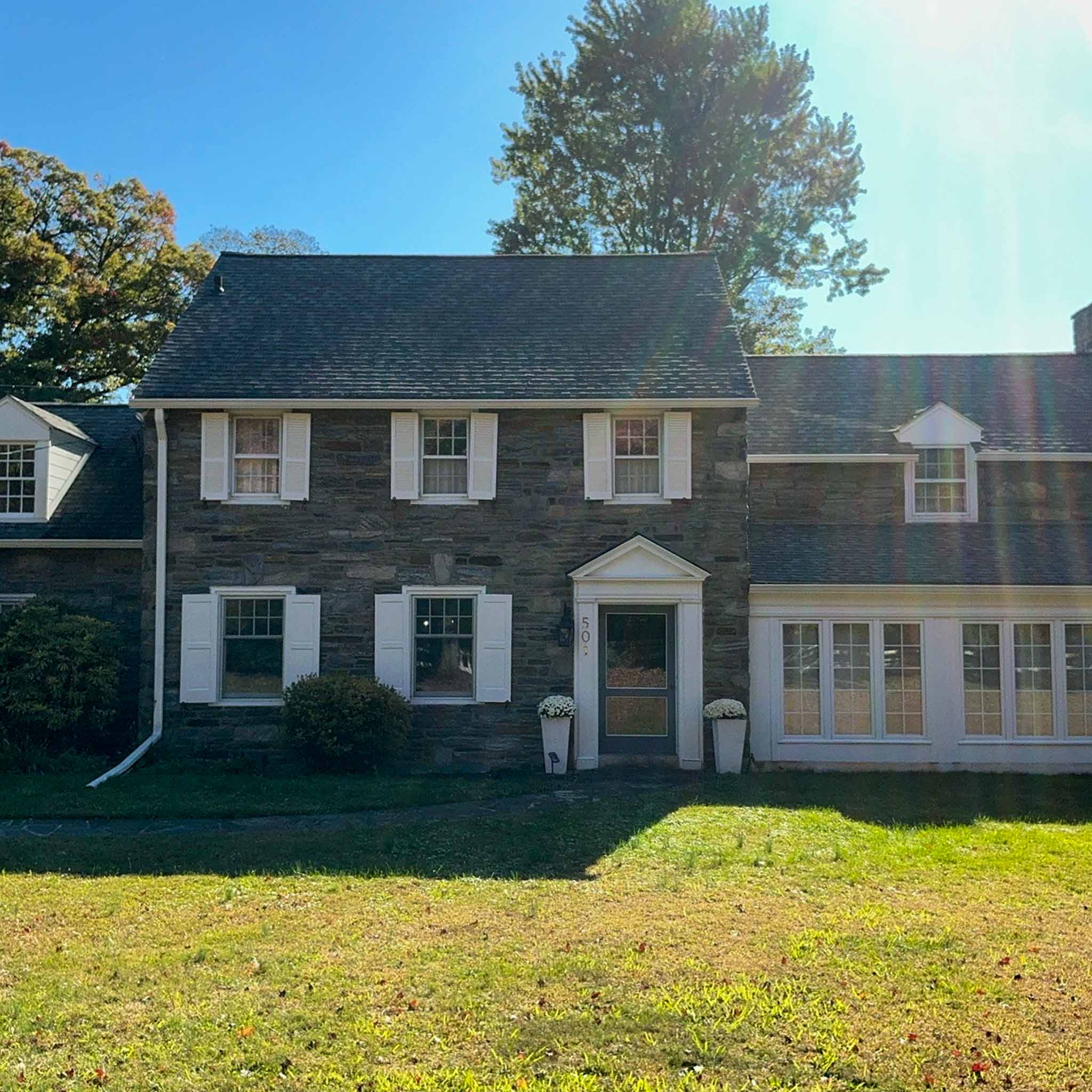 Fieldstone Colonial with white shutters, a pedimented entry and dormered roofline in Haverford, Montgomery County PA, inspected by ValueGuard home inspectors