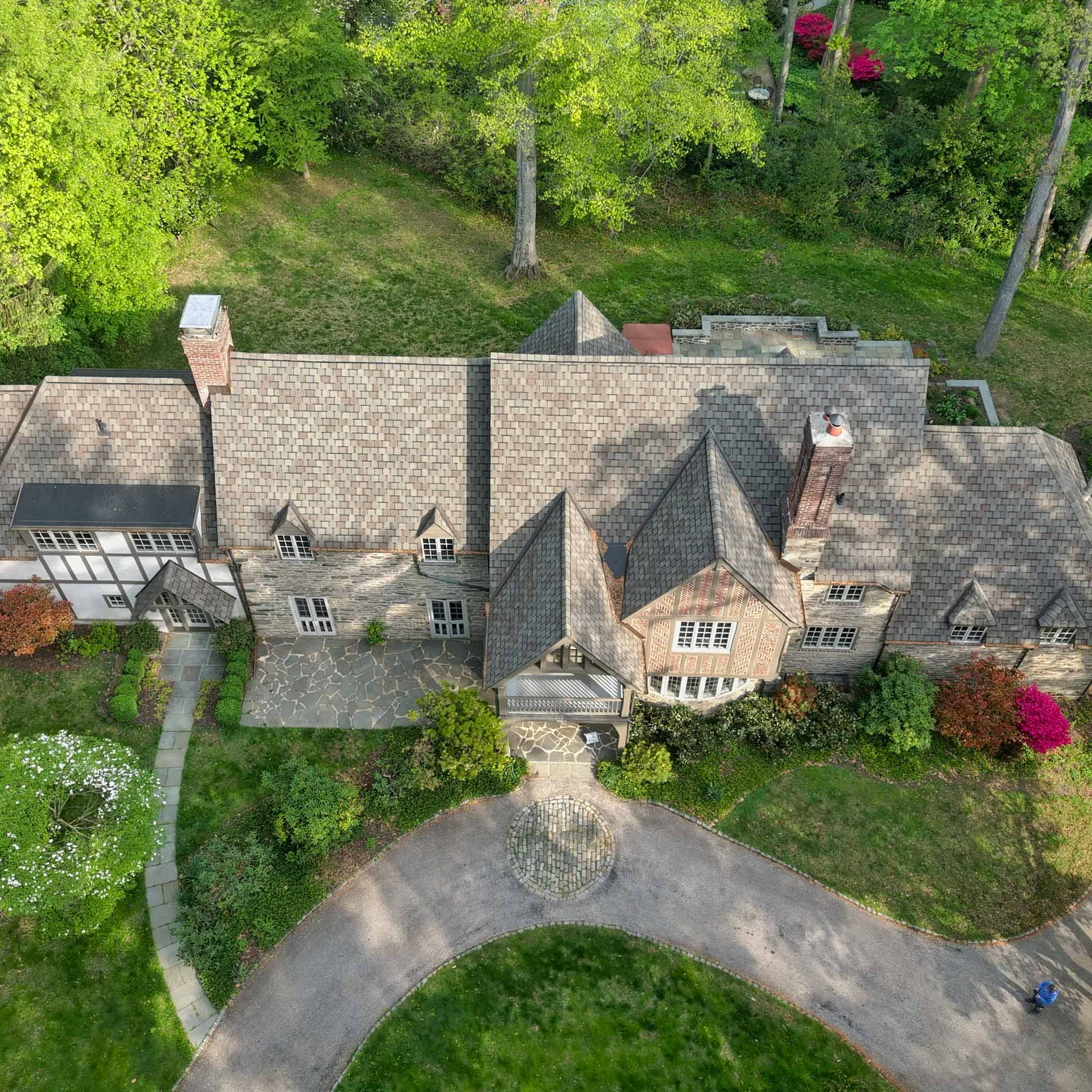 Aerial view of a stone Tudor estate with an expansive slate roof and half-timbered gables during a ValueGuard home inspection in Haverford on the Main Line
