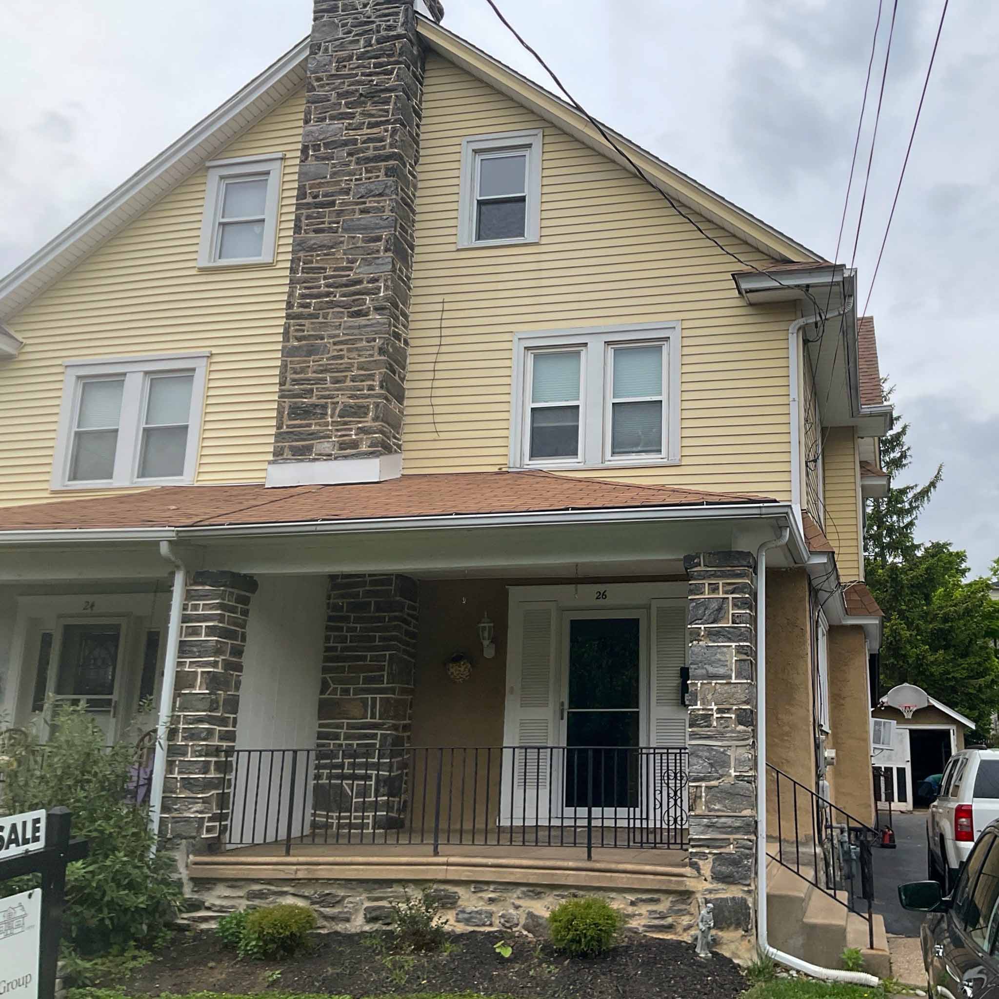 Yellow Havertown twin with full fieldstone chimney and stone porch piers inspected by ValueGuard home inspectors