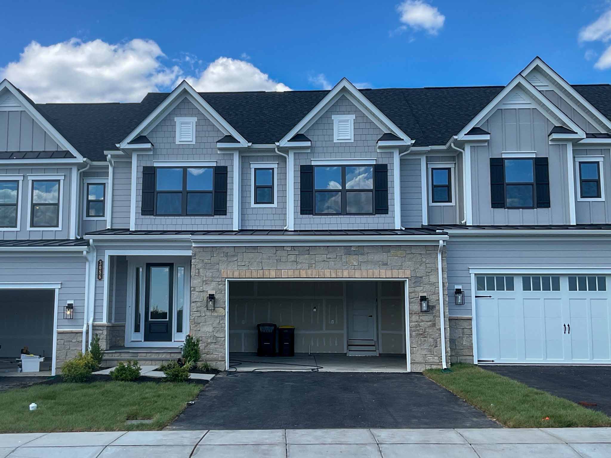 Newly built gray shake and board-and-batten townhome with a stone-faced garage in Huntingdon Valley inspected by ValueGuard home inspectors