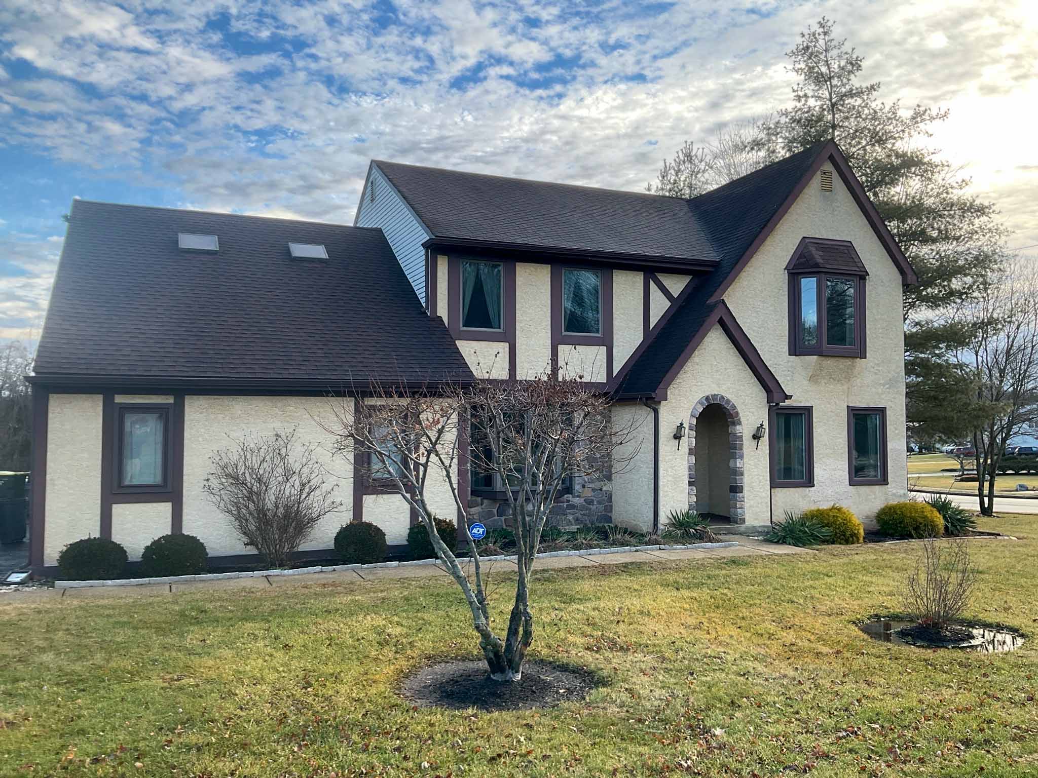 Stucco and half-timbered Tudor home with a stone-arched entry and asphalt-shingle roof in Huntingdon Valley inspected by a ValueGuard home inspector