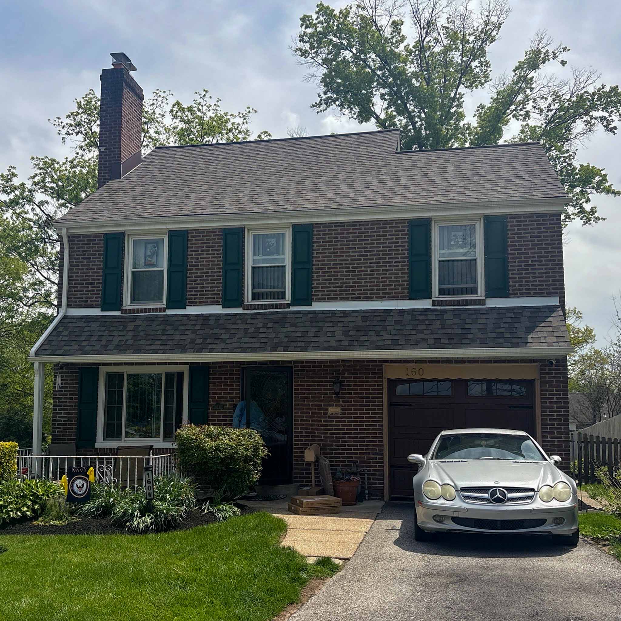 Mid-century brown brick Lansdowne colonial with attached garage and green shutters inspected by ValueGuard