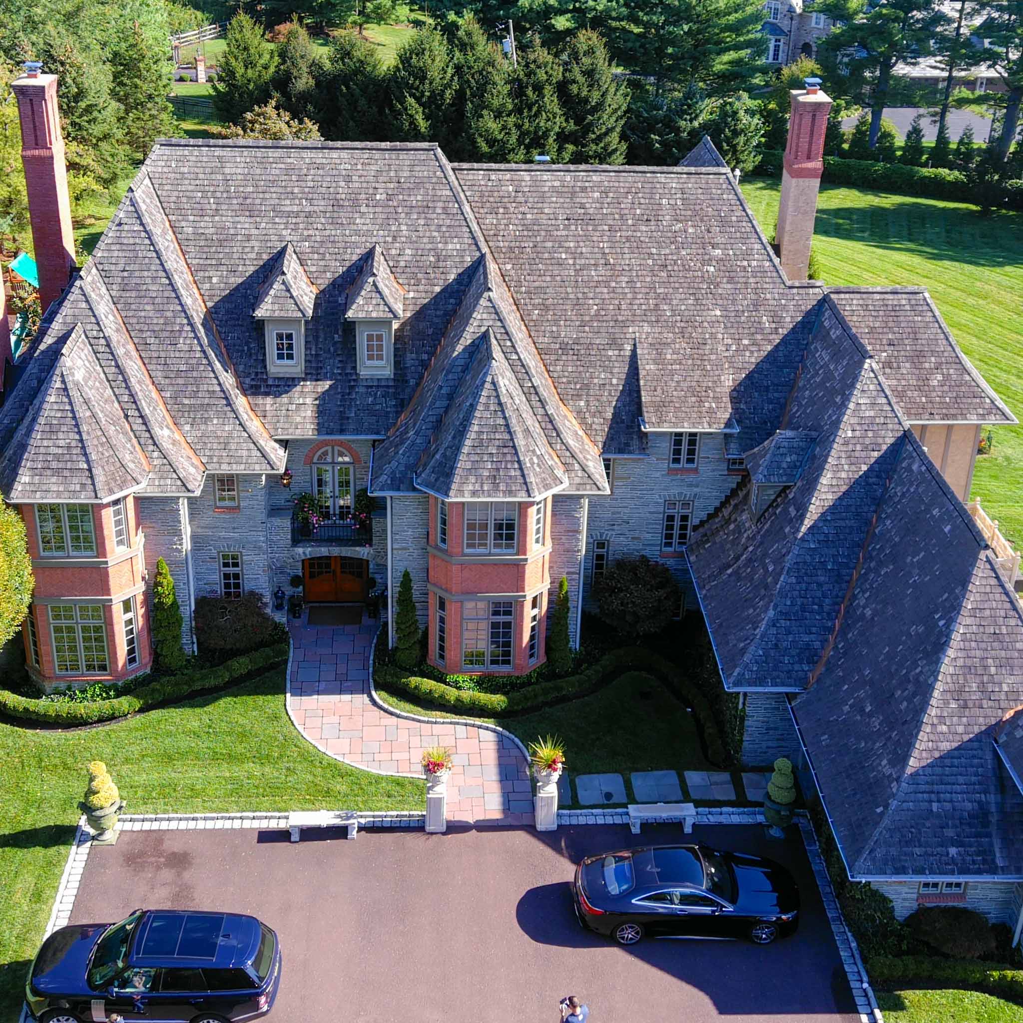 Aerial view of a grand stone French-manor estate with a steep slate roof and turrets during a ValueGuard home inspection on Philadelphia's Main Line
