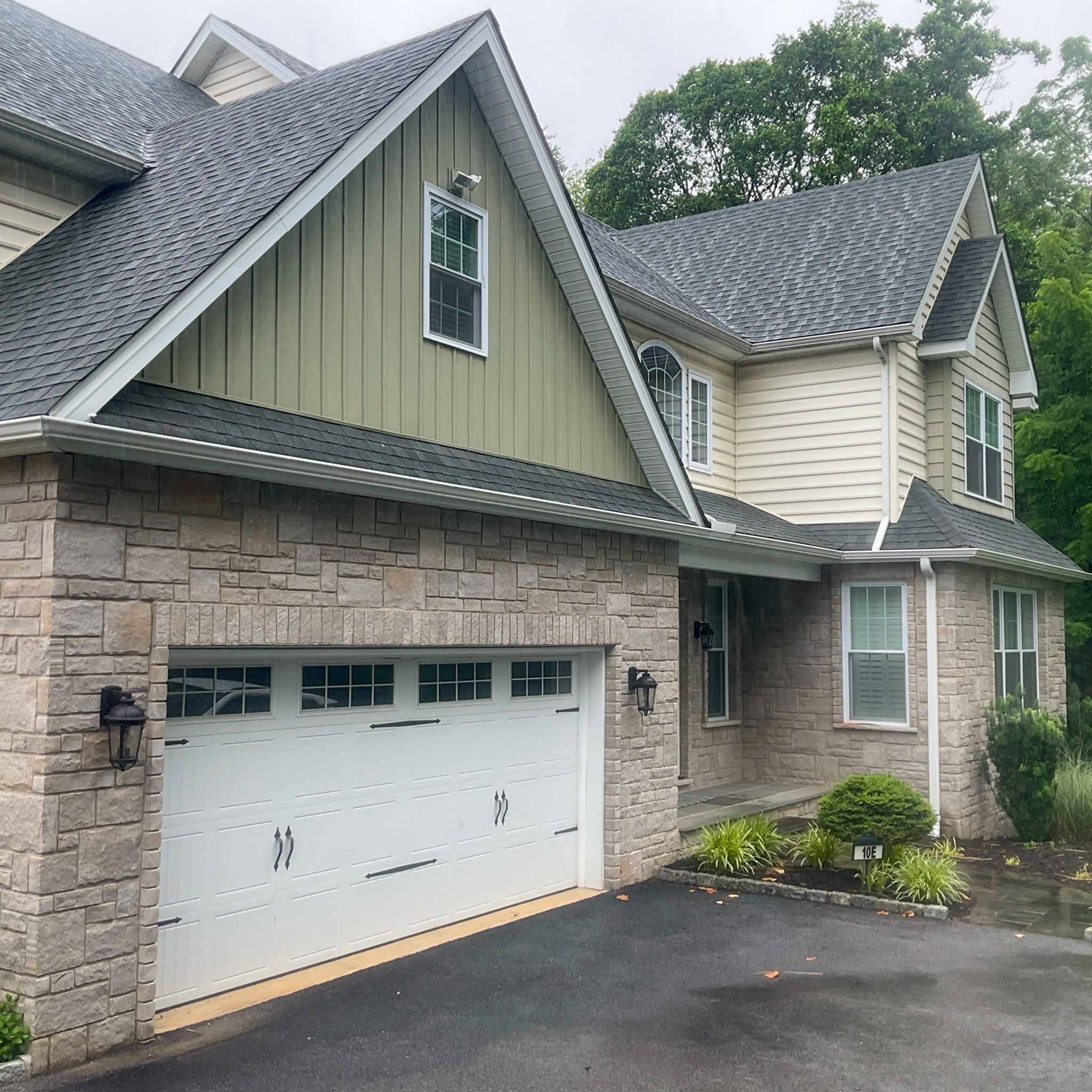 Paoli Home Inspection — Newer Stone-and-Siding Home Newer stone-and-siding home with a green board-and-batten gable and an attached two-car garage (unit 10E) in Paoli, Chester County PA, inspected by a ValueGuard home inspector