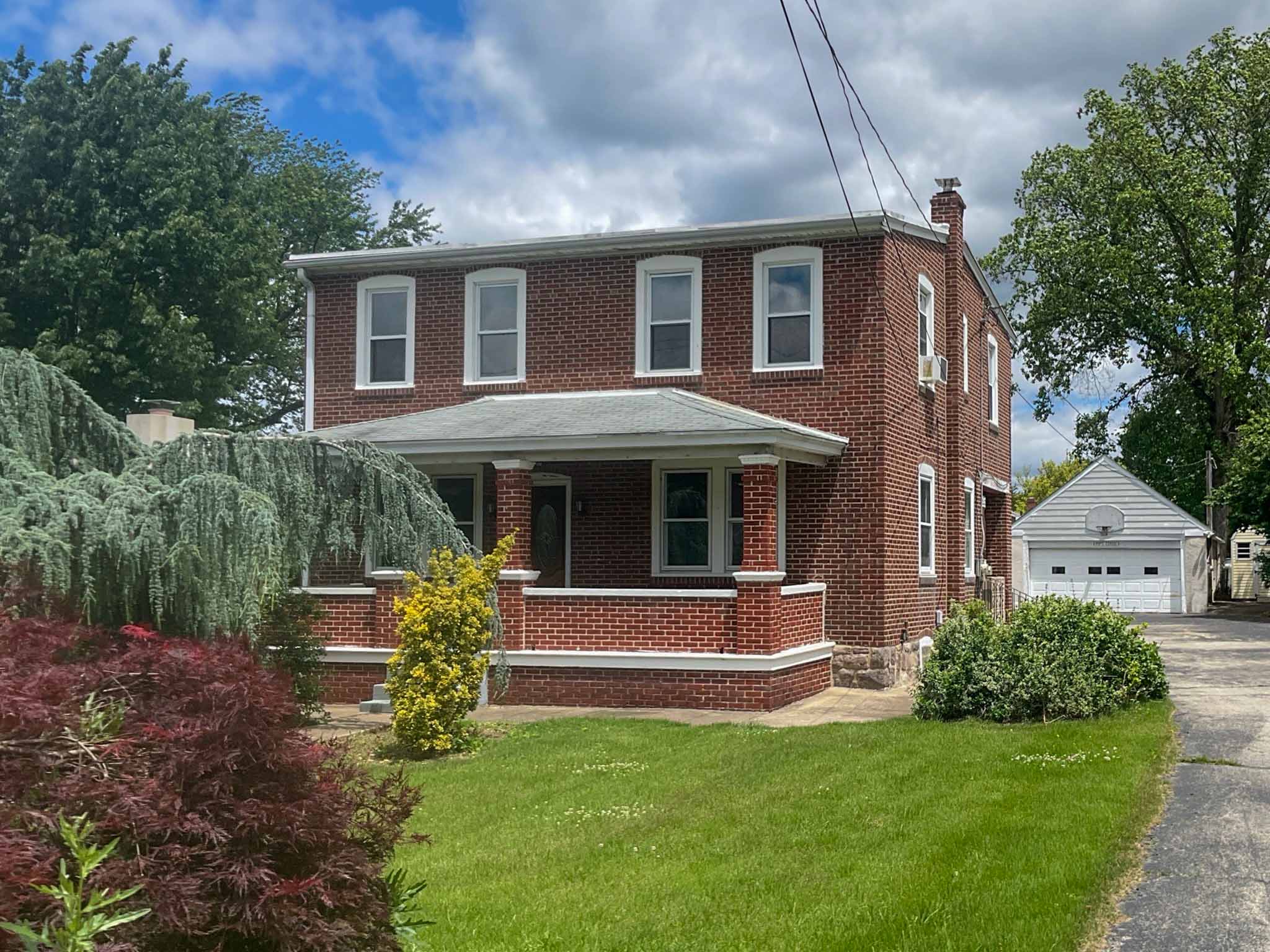 Older red-brick colonial home in Plymouth Meeting, PA with a covered front porch, inspected by a ValueGuard home inspector