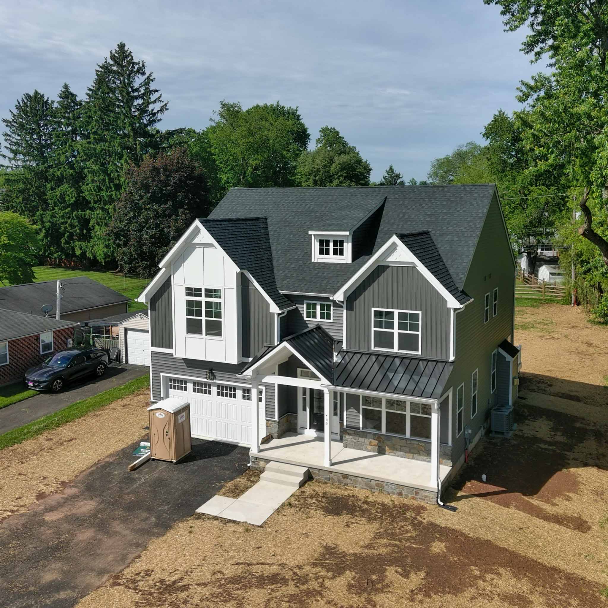 Newly built gray modern farmhouse in Plymouth Meeting, PA with board-and-batten siding and a standing-seam porch roof, inspected by a ValueGuard home inspector
