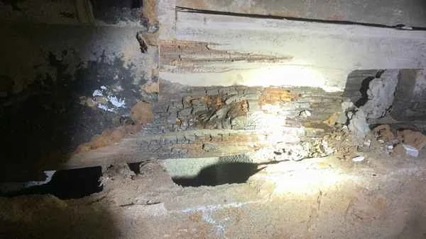 Rotted floor framing photographed deep inside a crawlspace during a post-settlement home inspection in Newtown Square PA