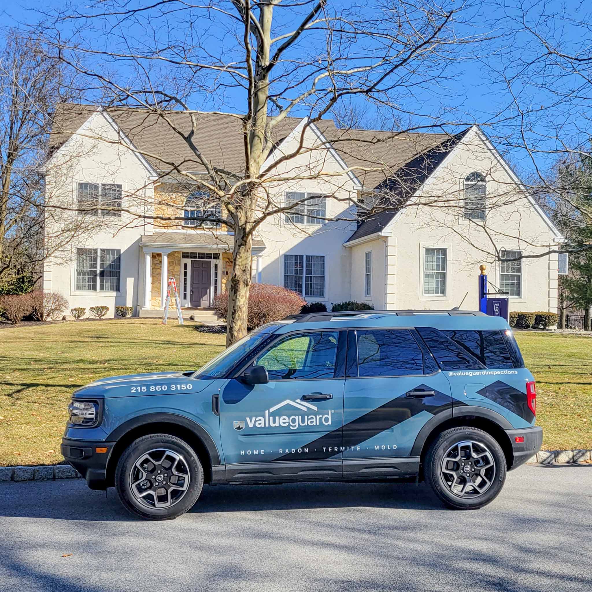A branded ValueGuard inspection SUV parked in front of a Delaware County home during a pre-listing inspection, with an inspector's ladder visible at the front door