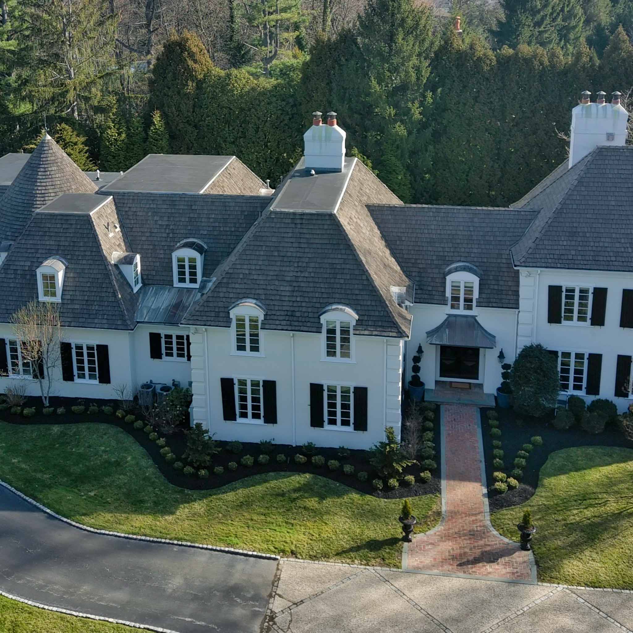 Large white stone-and-stucco French-style manor in Villanova with steep slate and wood-shake rooflines inspected by a ValueGuard home inspector