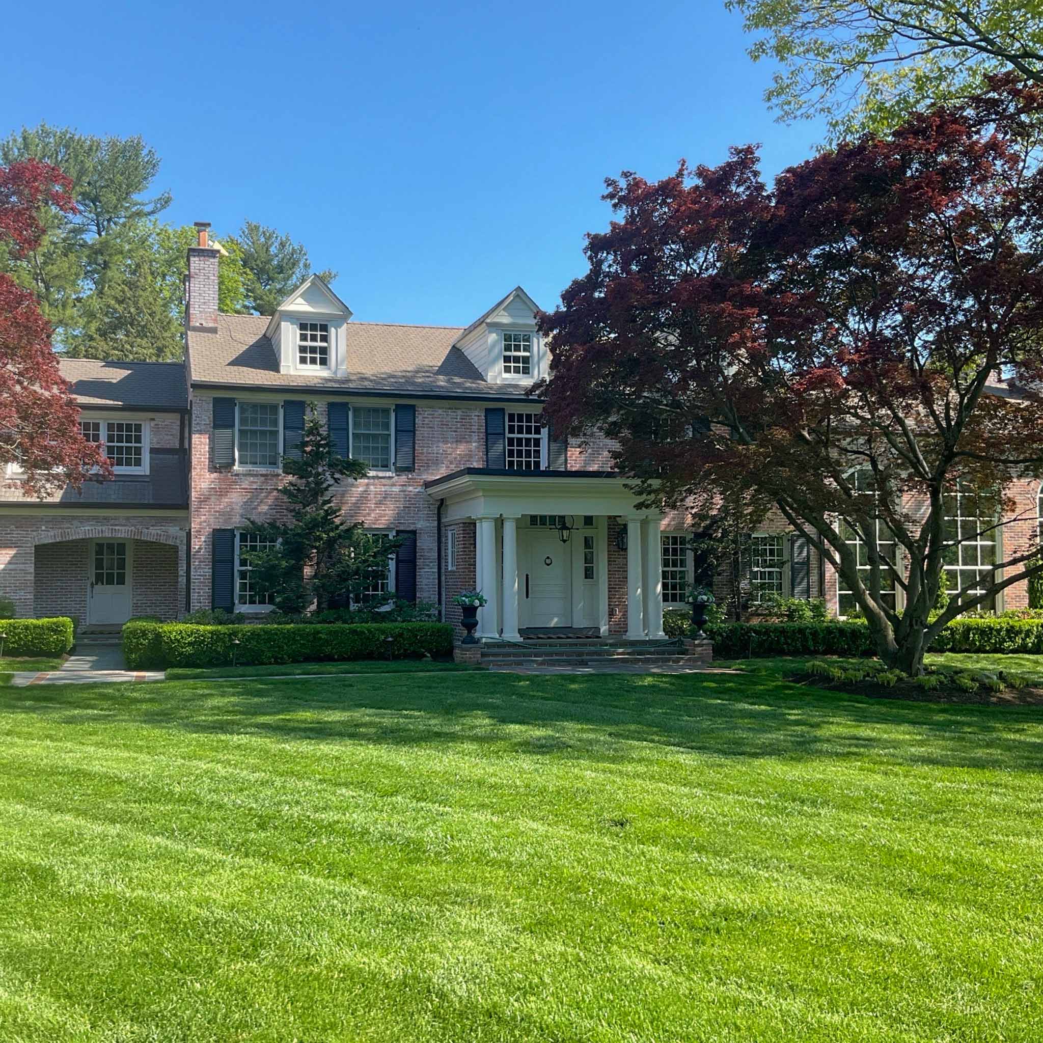 Brick center-hall colonial with black shutters and a white columned portico during a ValueGuard home inspection in Villanova on the Main Line