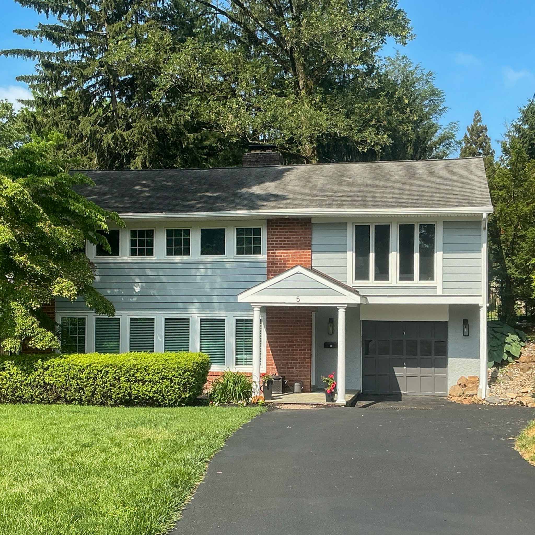 Expanded blue-gray split-level colonial with a brick chimney and attached garage in Wayne inspected by a ValueGuard home inspector