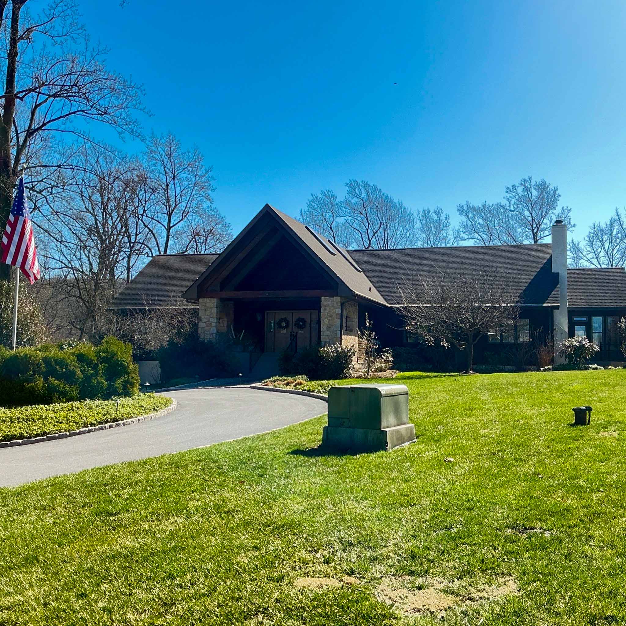 Sprawling stone-and-cedar ranch estate with a timber-and-stone gabled entry on a manicured Wayne lot inspected by ValueGuard home inspectors